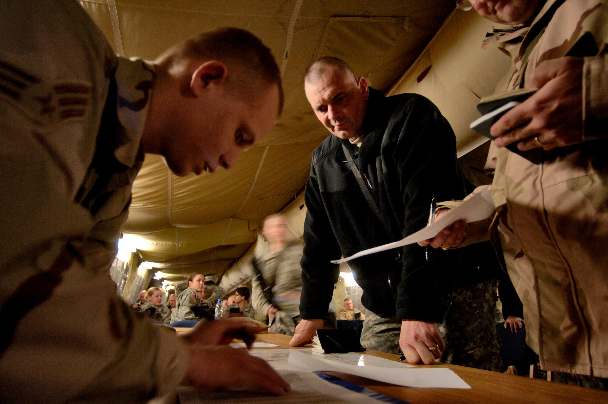 Senior Airman Michael Brown (left) provides Army Maj. Charles Stacowski and Army 1st Sergeant Eric Ramsett their lodging assignments at Manas Air Base, Kyrgyzstan, on Wednesday, March 15, 2006. Airman Brown is deployed to the 376th Expeditionary Services Squadron from the 99th Services Squadron at Nellis Air Force Base, Nev. (U.S. Air Force photo/Master Sgt. Lance Cheung)