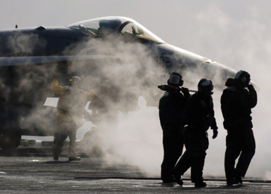 Flight deck crewmen are enveloped by steam as they ready an F/A-18F Super Hornet aircraft for a catapult launch from the aircraft carrier USS Abraham Lincoln (CVN-72) as the ship operates in the Sea of Japan on March 30, 2006. The Super Hornet is attached to Strike Fighter Squadron 151. 