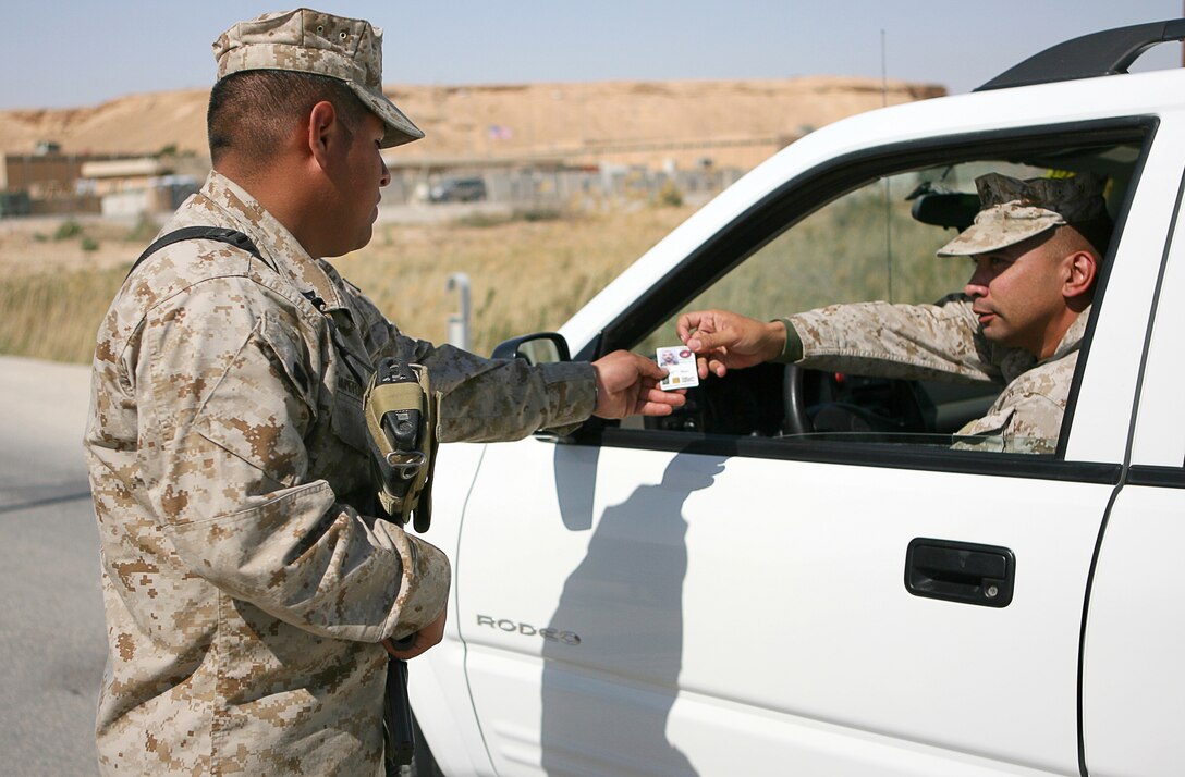 Force protection and other safety issues are a key concern for the Marines of Combat Logistics Battalion 7, 1st Marine Logistics Group, as they carry out their deployment at Al Asad Air Base, Iraq. While on guard, Lance Cpl. Nestor Tecuapetlahuanetl, a 23-year-old native of Los Angeles, checks the identification of all personnel who pass through his gate, whether they are in a vehicle, on a bicycle or walking March 30, 2006. Tecuapetlahuanetl, a truck driver with CLB 7â??s Engineer Company, is currently serving a two-week duty with the guard unit. Aside from their primary mission to provide logistical support to Marine and Iraqi forces in places like Ramadi, Hadithah, and Al Qaim, the battalion is also training Iraqi soldiers to carry out their own logistics operations.