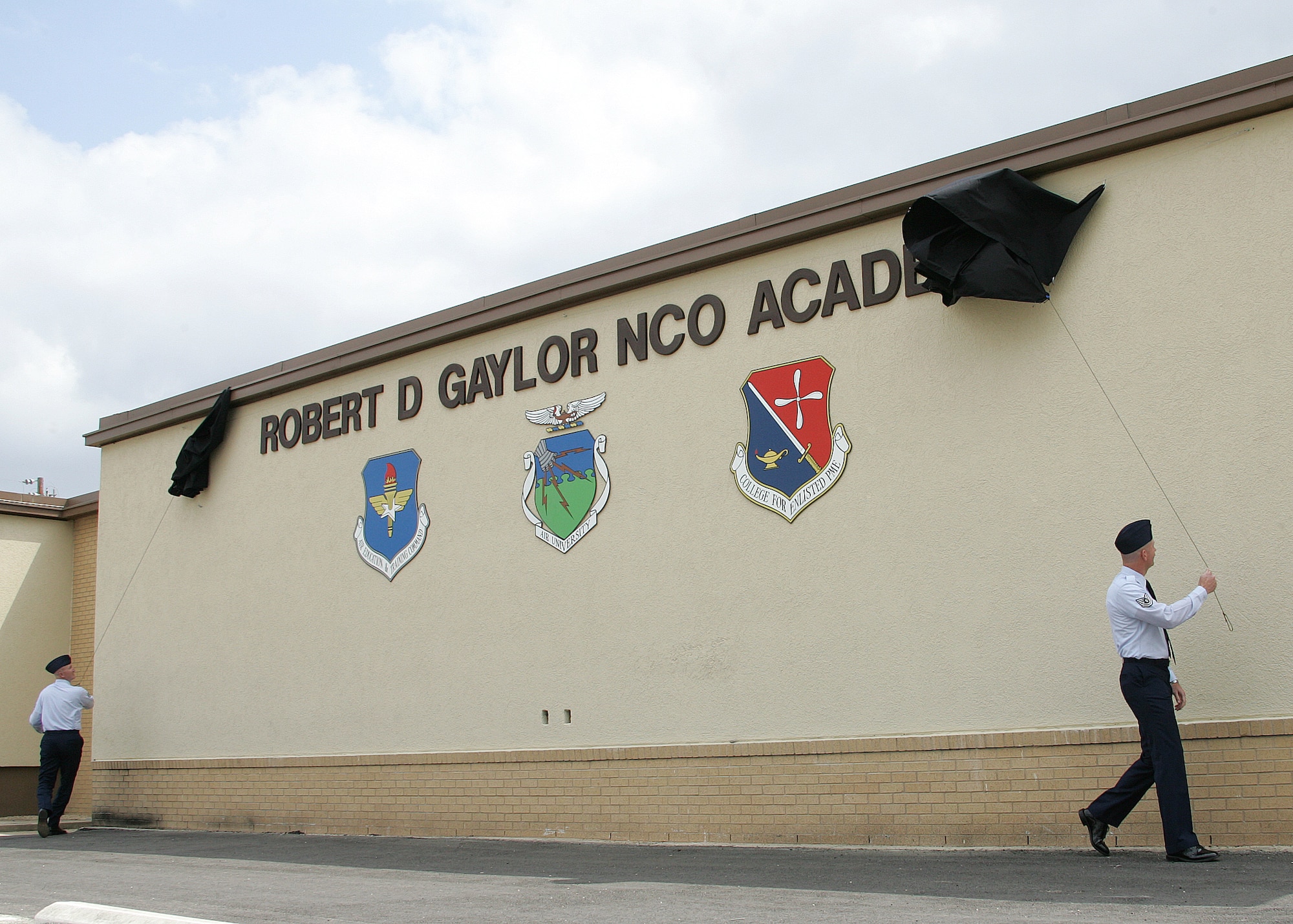 Tech. Sgts. Scott Ransom and William Pyle pull back the curtain unveiling the Robert D. Gaylor NCO Academy on Thursday, March 30, 2006, at Lackland Air Force Base, Texas.  The dedication was in honor of the fifth chief master sergeant of the Air Force, Robert D. Gaylor. (U.S. Air Force photo/Robbin Cresswell)