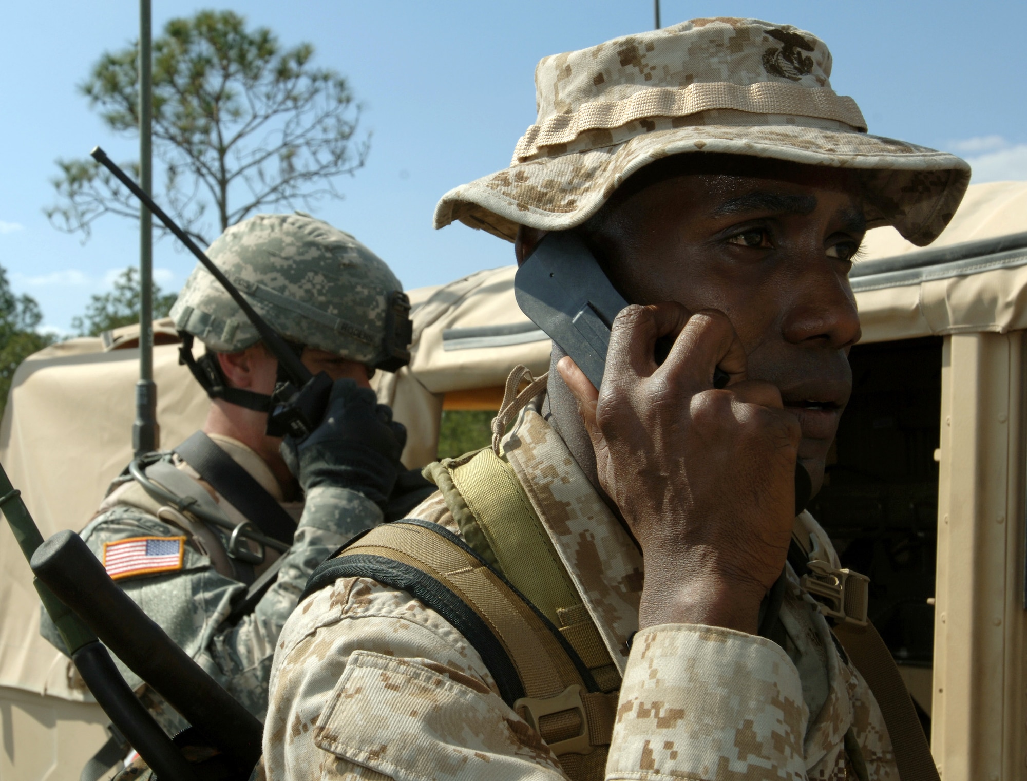 Marine Staff Sgt. Aamir Greene, right, communicates with aircraft using a PRC-117 radio while Army Staff Sgt. Jimmy Rogers coordinates with a 42-person scout patrol in the mock village at Avon Park, Fla., March 29, 2006, as part of Atlantic Strike III, a joint air and ground training event.  Sergeant Greene is with the 4th Air Naval Gunfire Liaison Company and Sergeant Rogers is with the 1st Cavalry Division at Fort Hood, Texas. (U.S. Air Force photo/Staff Sgt. Ashley S. Brokop)