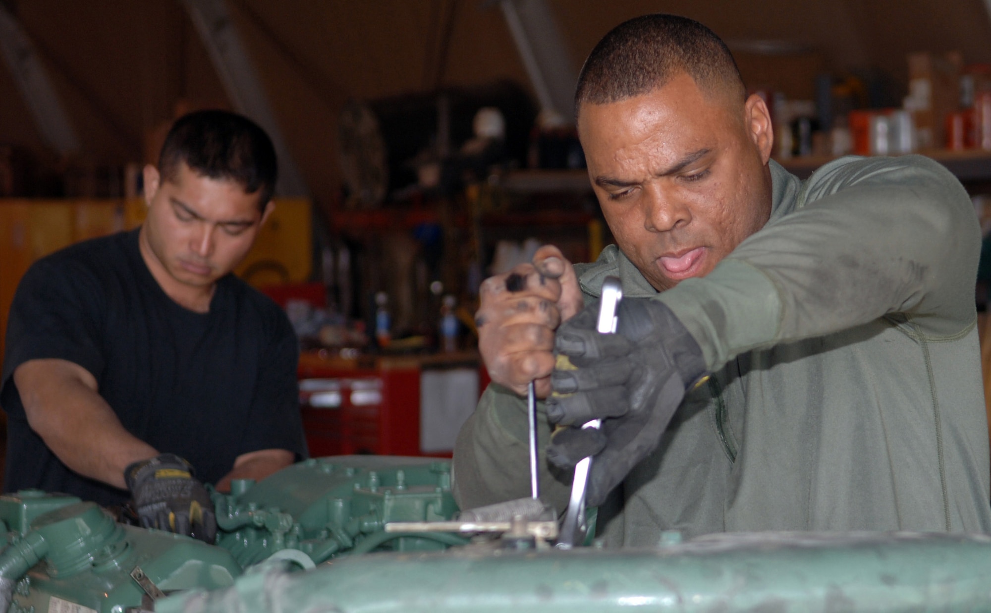 Staff Sgts. Andre McDonald, front, and Fernando Mendiola place engine coolant fittings from an old 60K aircraft loader engine onto a new one. The sergeants are assigned to the 455th Logistics Readiness Squadron vehicle management flight. Sergeant Mendiola is a material handling equipment mechanic and Sergeant McDonald is a multipurpose vehicle mechanic. (U.S. Air Force photo/Staff Sgt. Jennifer Redente) 
