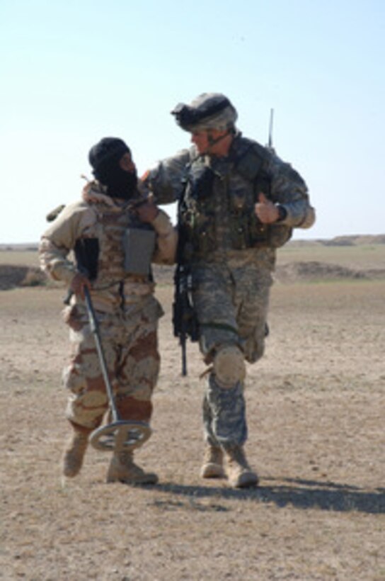 A U.S. Army soldier from Bravo Battery, 3rd Battalion, 320th Field Artillery Regiment and an Iraq army soldier from the 1st Battalion, 1st Brigade, 4th Division make small talk during a patrol in the Salah Ad Din Province, Iraq, on March 30, 2006. 
