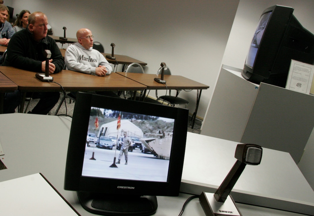 Kelly Kasal, left, and Kevin Kasal watch as their brother, Sgt. Maj. Bradley A. Kasal, is awarded the Navy Cross on May 1, 2006, via live video teleconference at the Southwestern Community College in Creston, Iowa. The VTC was arranged in order to allow Gerald Kasal, the Marine's severely ill father who couldn't travel, to witness the ceremony. Unfortunately, he passed away on April 30. Kasal, who was also promoted to the rank of sergeant major during the ceremony at Camp Pendleton, Calif., earned the Marine Corps' second highest award for combat heroism by selflessly shielding a Marine from an exploding grenade thus saving his life in Fallujah, Iraq, in November 2004. Kasal, a 39-year-old native of Afton, Iowa, is scheduled to return to his home state at the end of May to serves as the sergeant major of the Marine Corps recruiting station headquartered in Des Moines. (Photo by Staff Sgt. Bill Lisbon)