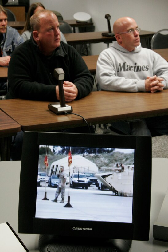 Kelly Kasal, left, and Kevin Kasal watch as their brother, Sgt. Maj. Bradley A. Kasal, is awarded the Navy Cross on May 1, 2006, via live video teleconference at the Southwestern Community College in Creston, Iowa. The VTC was arranged in order to allow Gerald Kasal, the Marine's severely ill father who couldn't travel, to witness the ceremony. Unfortunately, he passed away on April 30. Kasal, who was also promoted to the rank of sergeant major during the ceremony at Camp Pendleton, Calif., earned the Marine Corps' second highest award for combat heroism by selflessly shielding a Marine from an exploding grenade thus saving his life in Fallujah, Iraq, in November 2004. Kasal, a 39-year-old native of Afton, Iowa, is scheduled to return to his home state at the end of May to serves as the sergeant major of the Marine Corps recruiting station headquartered in Des Moines. (Photo by Staff Sgt. Bill Lisbon)