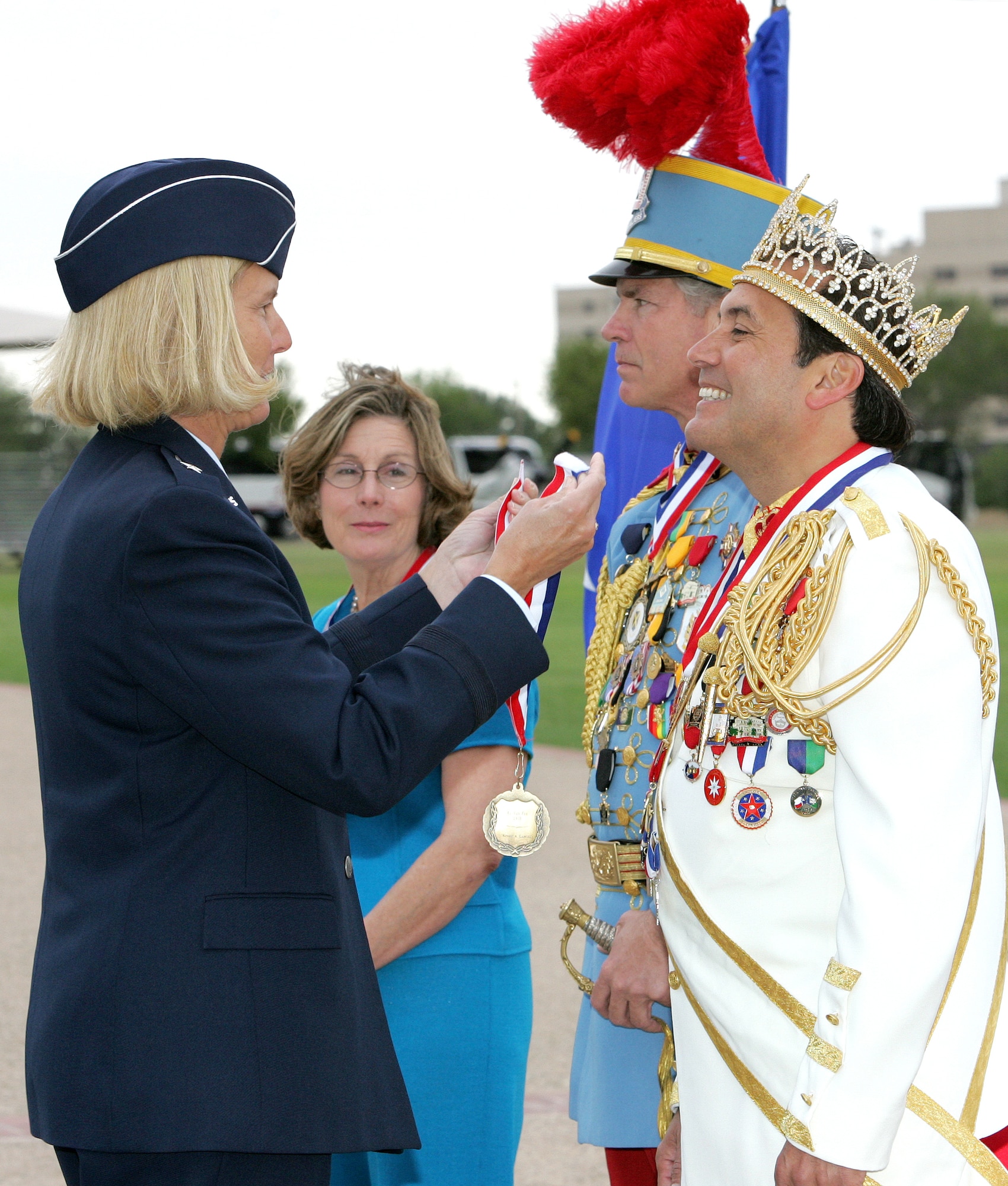 Brig. Gen. Mary Kay Hertog, 37th Training Wing commander at Lackland Air Force Base, Texas, presents El Rey Feo, Johnny Gabriel, with a Lackland medallion. Mr. Gabriel, along with Rick Shaw, King Antonio LXXXIV, and Mary West Traylor, Fiesta San Antonio Commission president, review a parade a Lackland on Wednesday, April 26, 2006.  The military parade was one of the many events held during Fiesta, a 10-day celebration to honor the memory of the heroes of the Alamo and the Battle of San Jacinto in 1836. (U.S. Air Force photo/Robbin Cresswell) 