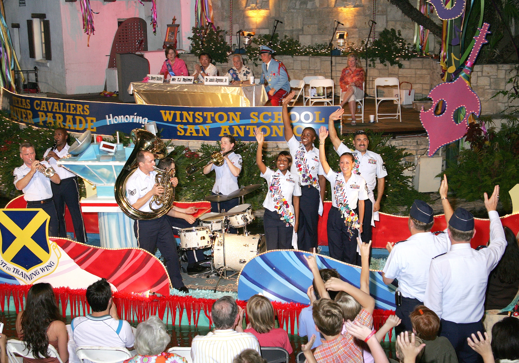 Military ambassadors with the 37th Training Wing at Lackland Air Force Base, Texas, and the 12th Flying Training Wing at Randolph AFB, Texas, roll down the river on a barge during the Texas Cavaliers River Parade in San Antonio on Monday, April 24, 2006.  This parade is one of several events held during Fiesta, a 10-day celebration to honor the memory of the heroes of the Alamo and the Battle of San Jacinto in 1836.  Also on the float are members of the Air Force Band of the West from Lackland. (U.S. Air Force photo/Robbin Cresswell)
