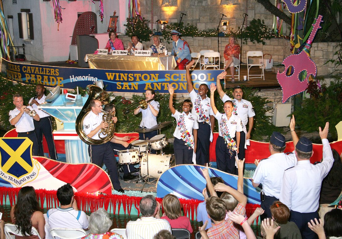 Military ambassadors with the 37th Training Wing at Lackland Air Force Base, Texas, and the 12th Flying Training Wing at Randolph AFB, Texas, roll down the river on a barge during the Texas Cavaliers River Parade in San Antonio on Monday, April 24, 2006.  This parade is one of several events held during Fiesta, a 10-day celebration to honor the memory of the heroes of the Alamo and the Battle of San Jacinto in 1836.  Also on the float are members of the Air Force Band of the West from Lackland. (U.S. Air Force photo/Robbin Cresswell)