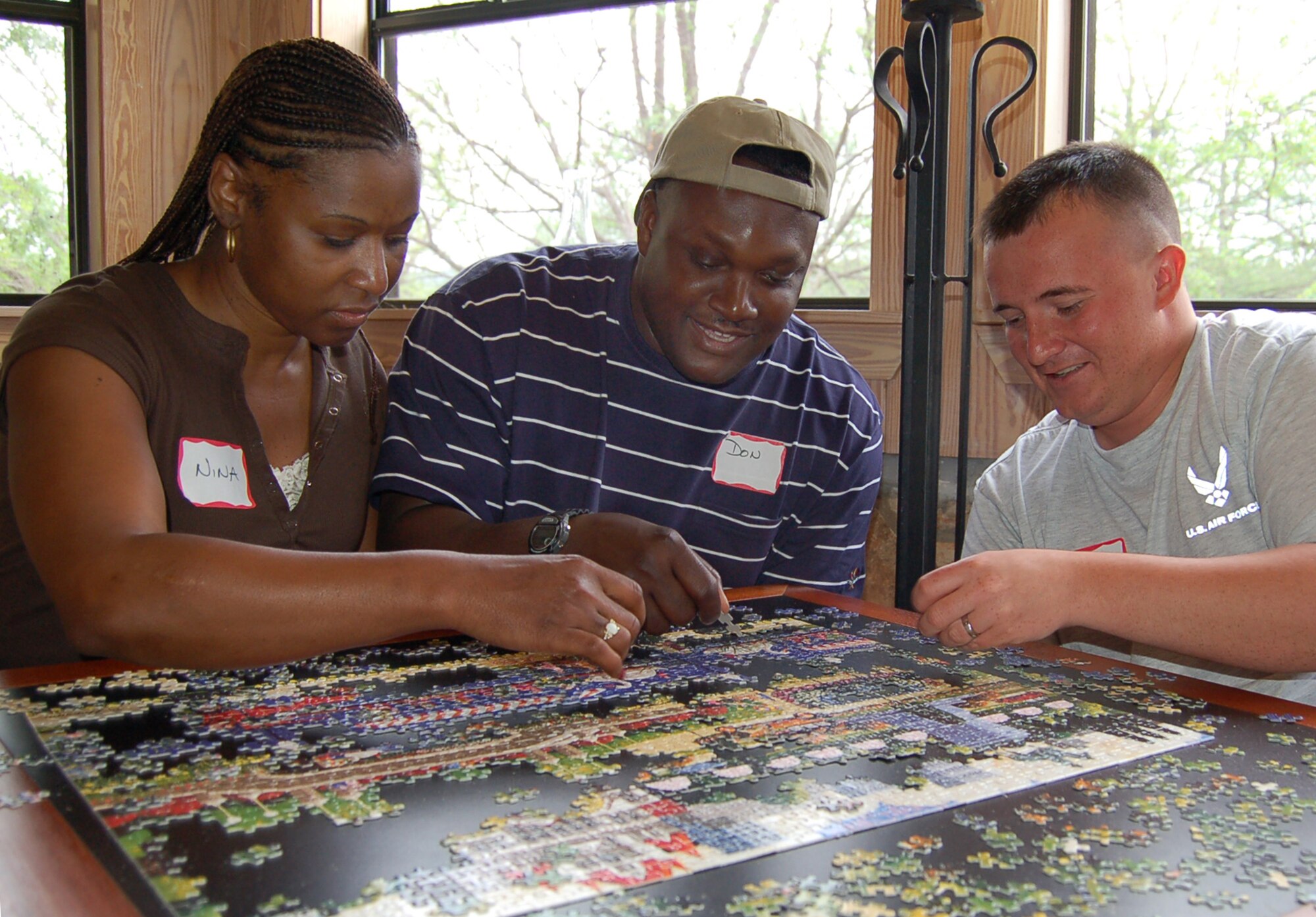 Nina and Master Sgt. Don Taylor build a 1,000-piece puzzle with Senior Airman Aaron Childs during a retreat at the Heart of the Hills Camp in Hunt, Texas, on Saturday, April 22, 2006. The retreat was hosted by the Military, Veteran and Family Assistance Foundation, helps couples reconnect after the military spouse returns from a deployment. (U.S. Air Force photo/Louis A. Arana-Barradas)