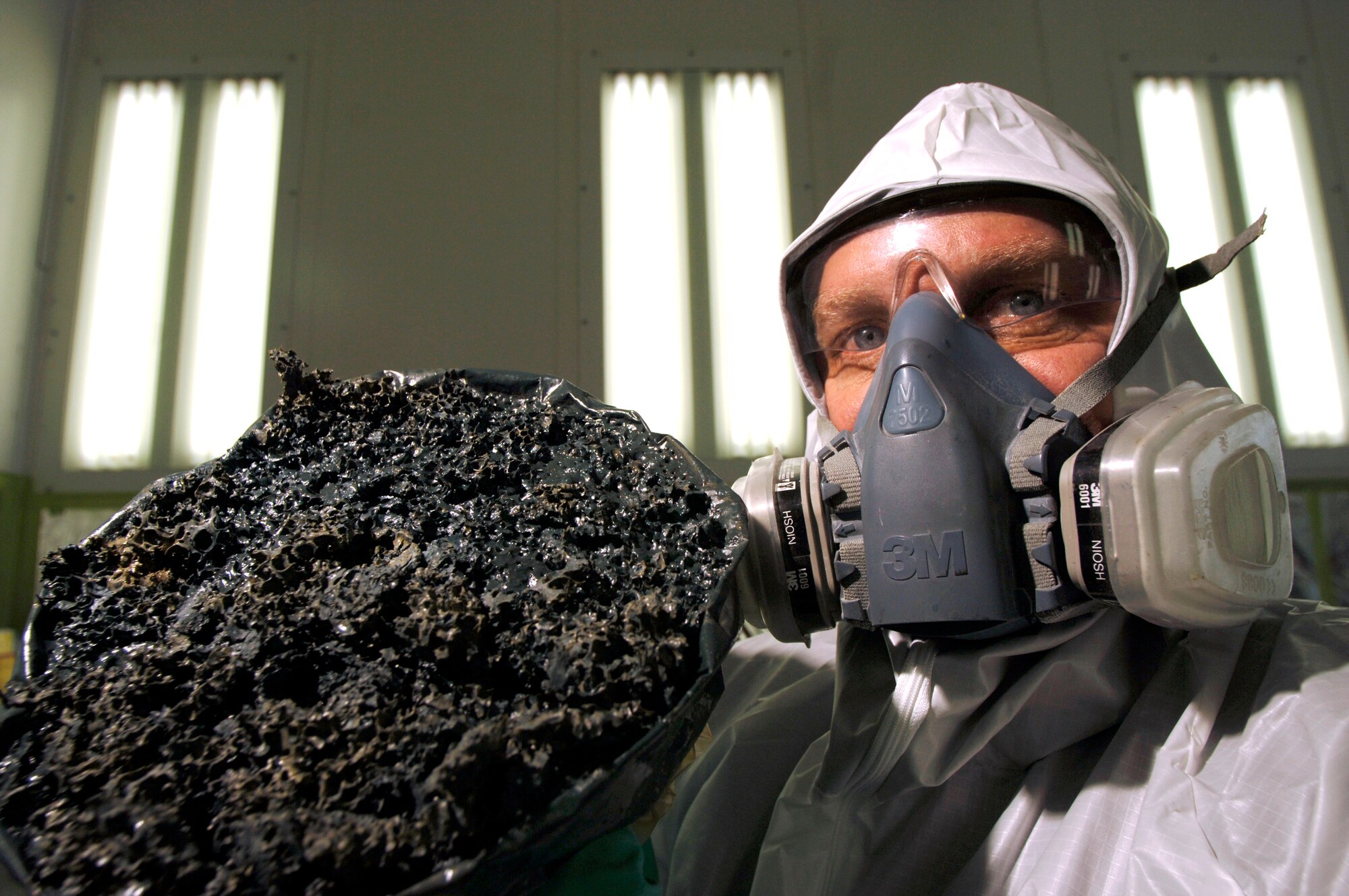 Christopher Reimer holds up what used to be 5 gallons of paint thinner. With a paint gun and equipment cleaner, the thinner within the paint is reduced into a 1-pound clump of rubbery residue called volatile organic waste compound. (U.S. Air Force photo/Tech. Sgt. Cecilio M. Ricardo Jr.)

