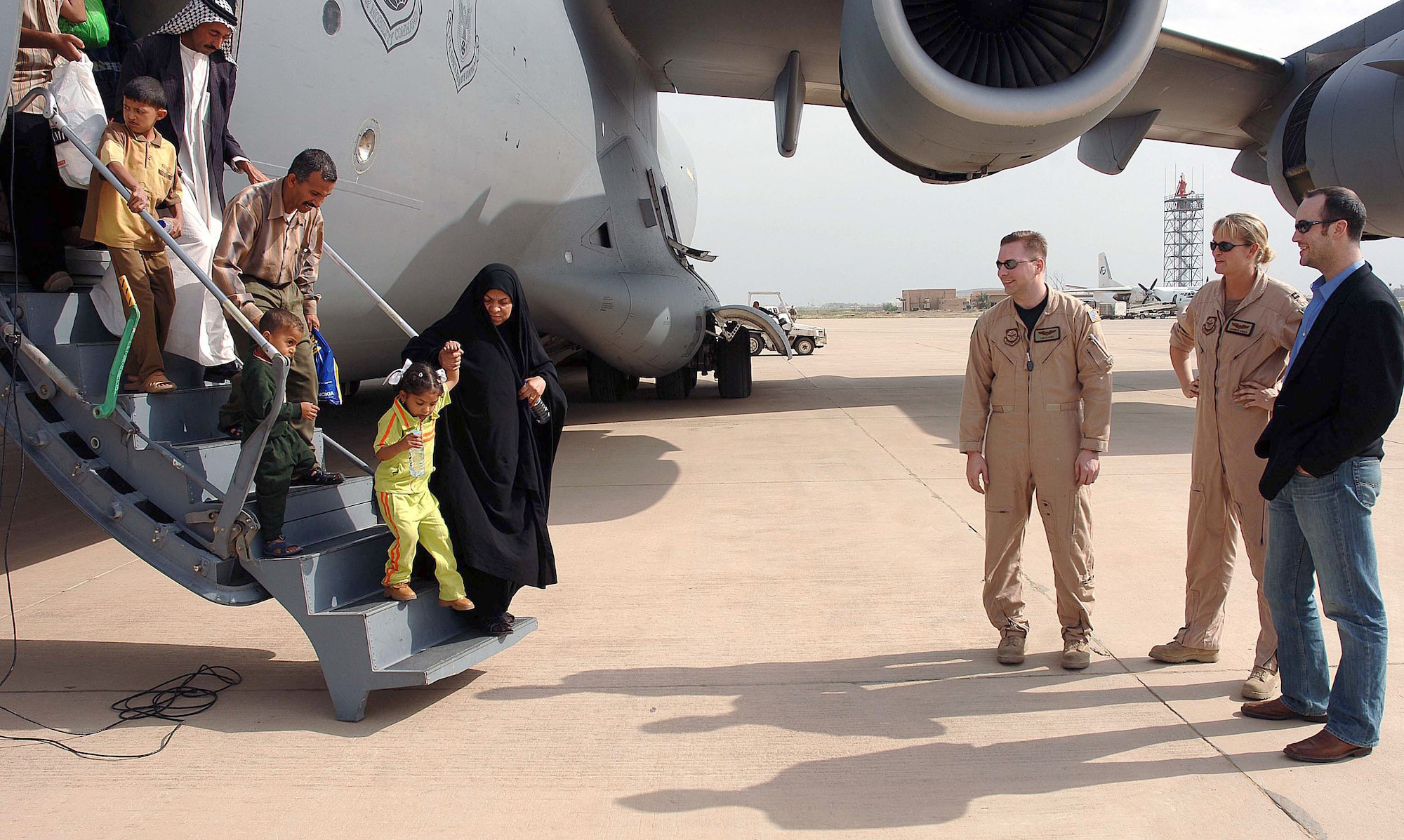 Iraqi children and their escorts leave an Air Force C-17 Globemaster III at Baghdad International Airport, Iraq, on Saturday, April 29, 2006, as Chris Anderson of Operation Smile and two crewmembers watch. Operation Smile provides corrective surgery for cleft palates and cleft lips. The program provided surgery in Amman, Jordan, to more than 100 Iraqi children. They were flown back to Iraq on the C-17. Mr. Anderson is an Operation Smile staff member based in the Middle East. (U.S. Air Force photo/Master Sgt. Will Ackerman)