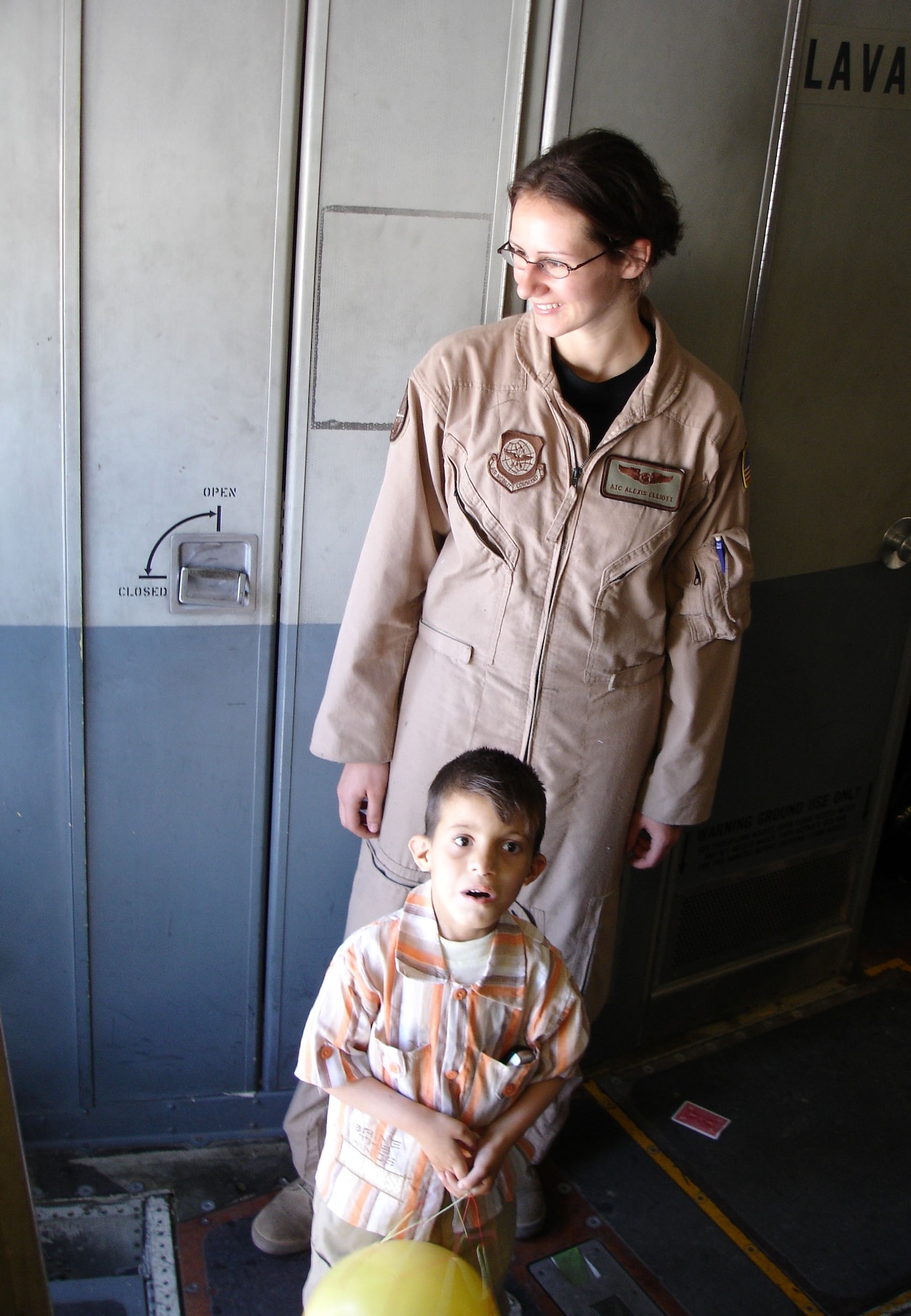Airman 1st Class Alexis Elliott, a C-17 loadmaster, greets Operation Smile passengers as one young Iraqi patient is awed by the cavernous cabin of the cargo aircraft.  Operation Smile is a non-governmental organization that treats children for cleft palate and cleft lip, a congenital birth defect.  On Saturday, the United States Air Force assisted Operation Smile in returning patients and their families to Iraq from Jordan, where the patients had received surgery. (U.S. Air Force Photograph by Maj. Robert Palmer)

