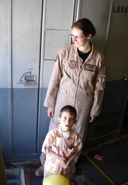 Airman 1st Class Alexis Elliott, a C-17 loadmaster, greets Operation Smile passengers as one young Iraqi patient is awed by the cavernous cabin of the cargo aircraft.  Operation Smile is a non-governmental organization that treats children for cleft palate and cleft lip, a congenital birth defect.  On Saturday, the United States Air Force assisted Operation Smile in returning patients and their families to Iraq from Jordan, where the patients had received surgery. (U.S. Air Force Photograph by Maj. Robert Palmer)
