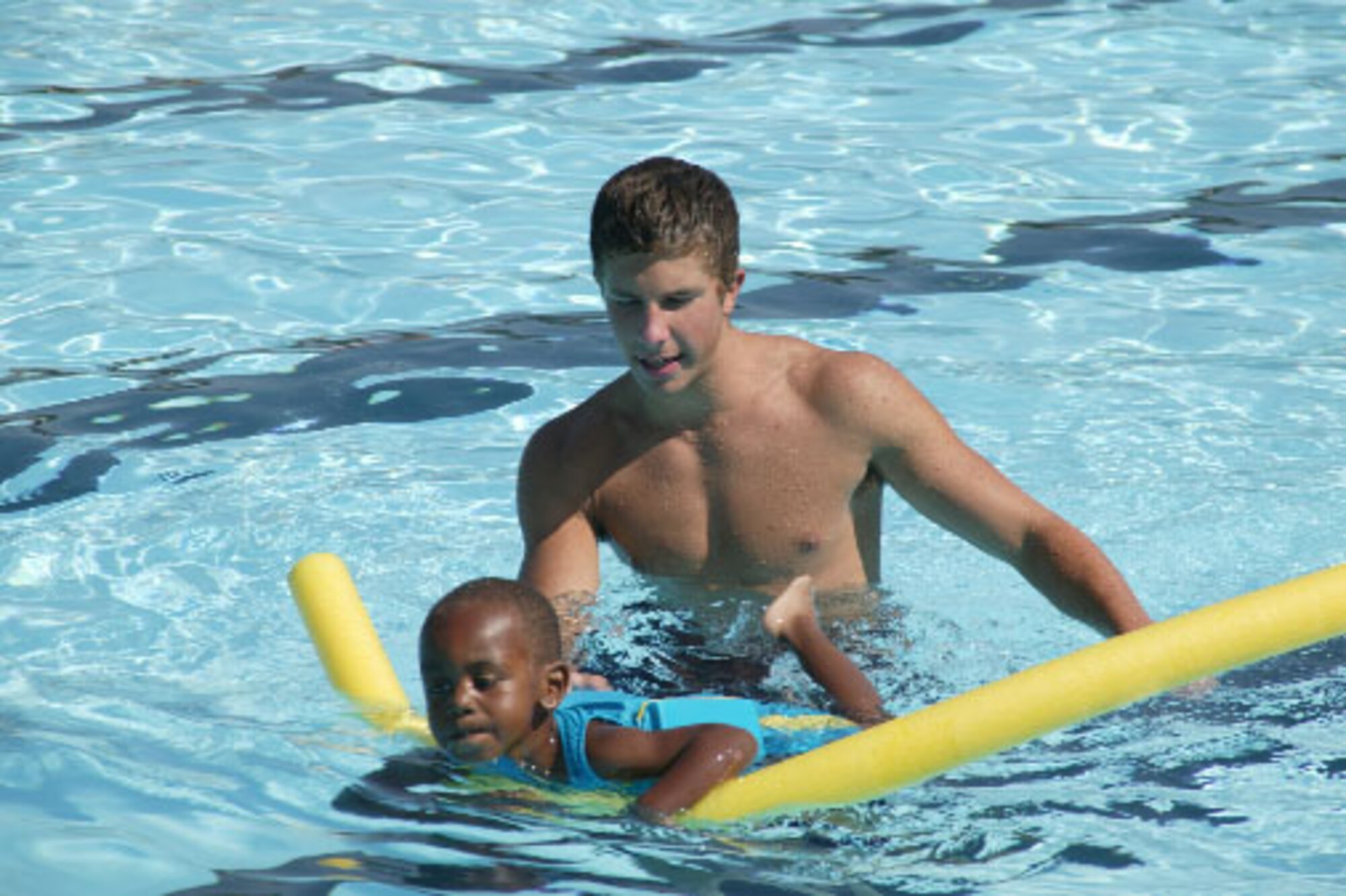 Garrett Williamson (right), a lifeguard at Woodland Pool, helps beginner swimmer Taylor, son of retired Army staff sergeants Francene and Tommy Reed, get used to the water in summer 2004.  (U.S. AIr Force Photo/Senior Airman Susan Penning)