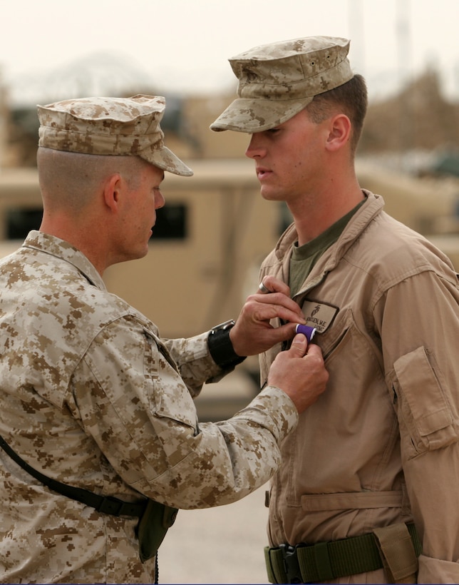 On May 1, 2006, United States Marine Corps Lieutenant Colonel James B. Hanlon (left) awards the Purple Heart Medal to Lance Corporal Matthias E. Knudsen (right); from Third Marine Air Wing (III MAW), Marine Wing Support Squadron 374 (MWSS-374), Military Police Company (MP CO); at Camp al Taqaddum in the al Anbar Province of Iraq.  (Official USMC photo by Corporal Samantha L. Jones, First Marine Logistics Group, Combat Camera; 060501-M-3658J-006)