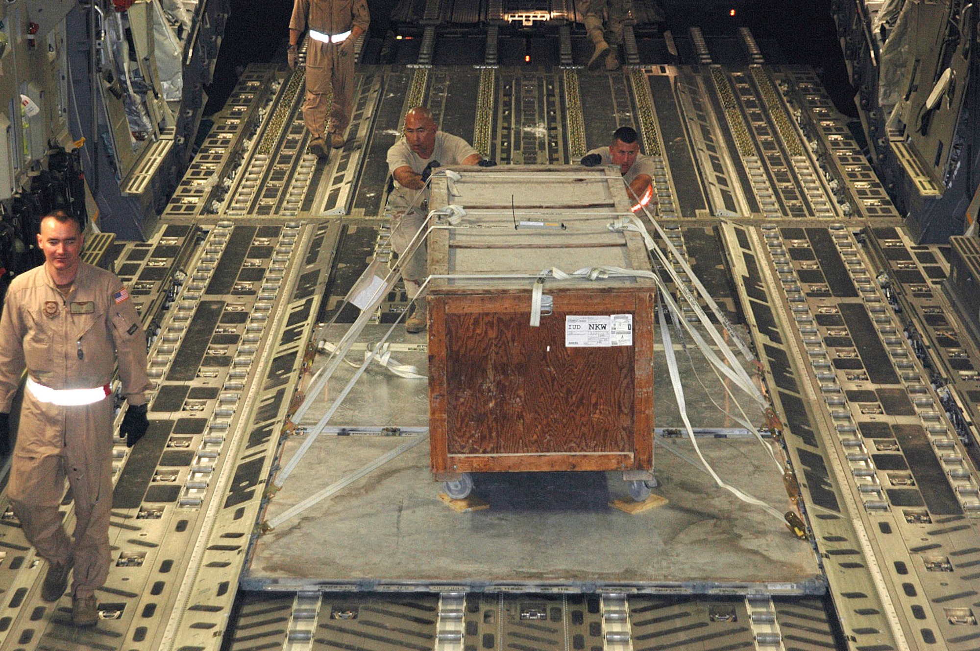 Airmen from the 380th Air Expeditionary Wing air terminal operations center shove a pallet of cargo onto a C-17 Globemaster III before a Southwest Asia mission. Master Sgt. Bill Lambert (left), a C-17 loadmaster, monitors the task. The sergeant and aircraft are with Detachment 2, 817th Expeditionary Airlift Squadron. The unit flies C-17 Globemaster IIIs throughout the region, carrying troops and supplies. (U.S. Air Force photo/Maj. Ann Peru Knabe) 