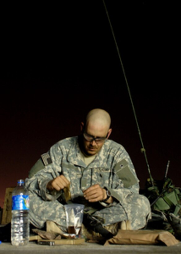 A U.S. Army soldier eats a Meal, Ready to Eat on the tarmac at Camp Taji, Iraq, before taking part in an air assault mission on April 28, 2006. 