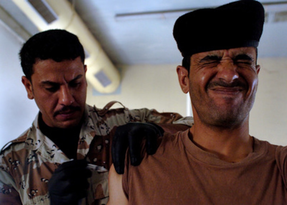 An Iraqi army soldier winces as an Iraqi army medic vaccinates him during a mass immunization for tetanus, typhoid and meningitis at Camp Taji, Iraq, on May 1, 2006. The soldiers are from Iraqís 9th Mechanized Division. 