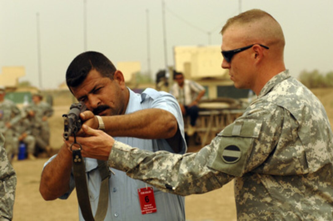 A soldier from the U.S. Army's 988th Military Police Company trains an Iraqi police officer on how to properly hold a weapon during a two-week basic military training course at Forward Operating Base Kalsu, Iraq, on May 2, 2006. 