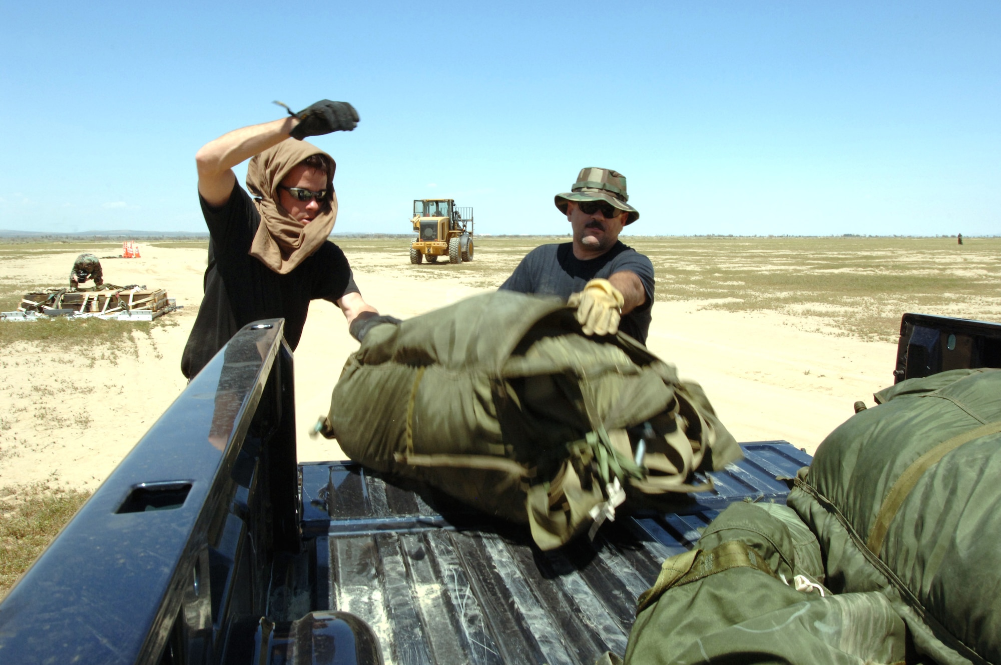 Senior Airmen Mark Richwine and Cenobio Alvarez load a parachute used to extract a Type 5 heavy pallet that was dropped from a C-130J Hercules at Edwards Air Force Base, Calif., on Sunday, April 30, 2006. The mission was part of a test to certify the aircraft's capability to drop this type of pallet. Guard, Reserve and active-duty aircrews from Channel Islands Air National Guard Base, Calif.; Little Rock AFB, Ark.; and Keesler AFB, Miss., participated in the certification. This was the first time the "J" model dropped a Type 5 pallet. The three Airmen are with the 146th Aerial Port Squadron at Channel Islands ANGB. (U.S. Air Force photo/Tech Sgt Dave Buttner)