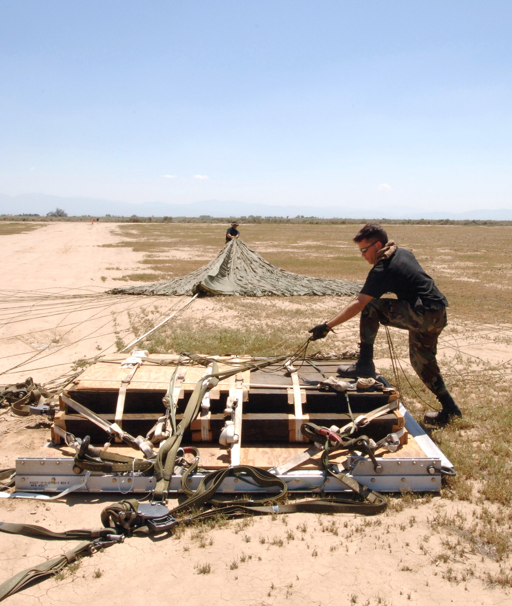 Senior Airman Mark Richwine disconnects the parachute from a Type 5 heavy pallet after it landed at Edwards Air Force Base, Calif., on Sunday, April 30, 2006. The pallet had been dropped from a C-130J Hercules as part of a test to certify the aircraft's capability to drop this type of pallet. Guard, Reserve and active-duty aircrews from Channel Islands Air National Guard Base, Calif.; Little Rock AFB, Ark.; and Keesler AFB, Miss., participated in the certification. This was the first time the "J" model dropped a Type 5 pallet. Airman Richwine is with the 146th Aerial Port Squadron at Channel Islands ANGB. (U.S. Air Force photo/Tech. Sgt. Dave Buttner)