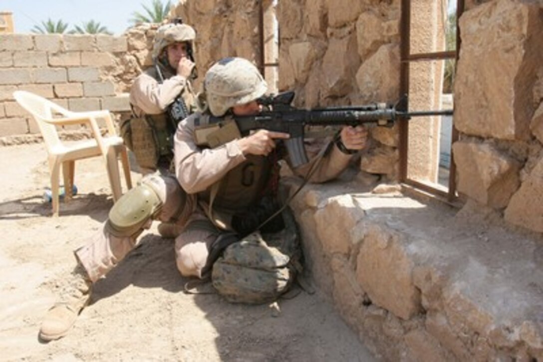 U.S. Marine Corps Cpl. Joseph Digloramo (right) provides overhead security while seeking cover from indirect small-arms fire during an operation to prevent and disrupt insurgency activity in Ar Ramadi, Iraq, on April 25, 2006. Digloramo is assigned as a combat correspondent with India Company, 3rd Battalion, 8th Marines. 