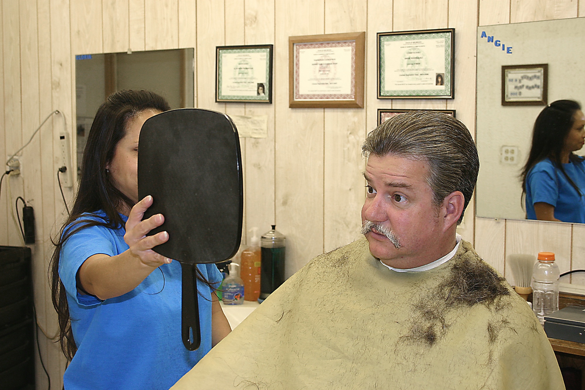 CANNON AIR FORCE BASE, N.M. - Sam Irons, 27th Comptroller Squadron, checks his new look after a haircut Monday. After retiring from the Air Force two years ago, Mr. Irons grew his hair for a special cause — Locks of Love. (U.S. Air Force photo by Janet Taylor-Birkey)