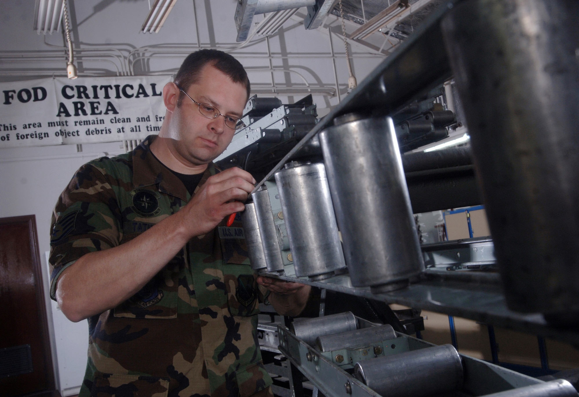 Staff Sgt. Elijah Tatman checks a C-130 Hercules roller conveyor for deformities and corrosion during an inspection at Yokota Air Base, Japan, on Wednesday, May 3, 2006. The cargo handling system is inspected at least twice a year. Sergeant Tatman is a C-130 crew chief with the 374th Aircraft Maintenance Squadron. (U.S. Air Force photo/Val Gempis)