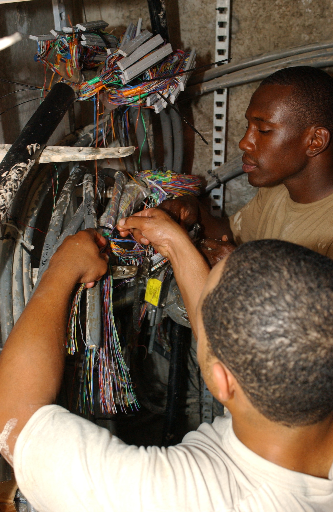 Staff Sgt. Benjamin Puryear (left) and Senior Airman Jonathan Williams splice copper cables on a 710 splice machine. Both are from 407th Expeditionary Communications Squadron's Base Information Infrastructure shop at Ali Base, Iraq. (U.S. Air Force photo/Master Sgt. Jon Hanson)