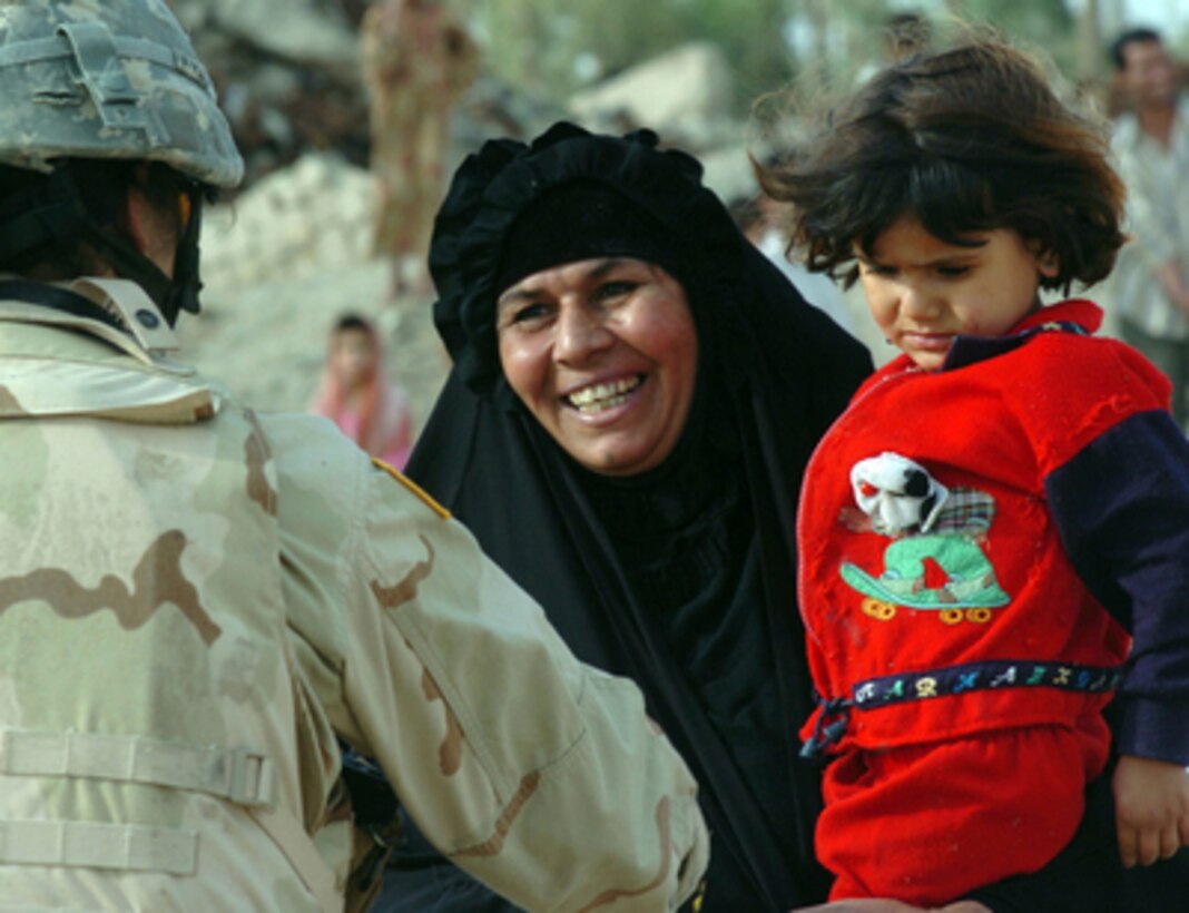 An Iraqi woman beams with gratitude as U.S. Army Pfc. Gina Lua hands her humanitarian assistance bags of food and water in Kamaliya, Iraq, on April 27, 2006. Lua is attached to Delta Company, 3rd Battalion, 67th Armored Regiment, 4th Brigade, 101st Airborne Division. 
