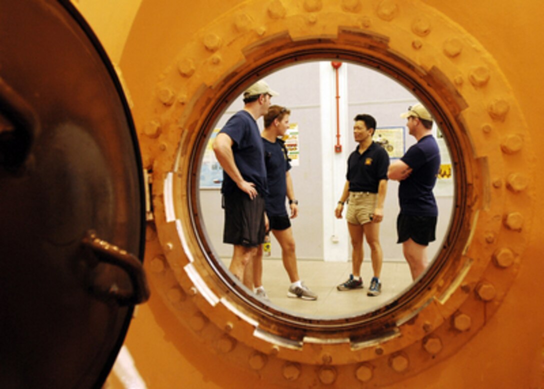U.S. Navy Explosive Ordnance Disposal technicians discuss recompression therapy techniques with a Singaporean Navy chief warrant officer outside a WWII-era British hyperbaric chamber in Singapore on May 2, 2006. Explosive Ordnance Disposal, or EOD, technicians from EOD Mobile Unit 11, Detachment 9, based out of Whidbey Island, Wash., are conducting joint training exercises with the Singapore Naval Diving Unit. The detachment is deployed aboard the aircraft carrier USS Abraham Lincoln (CVN 72). 