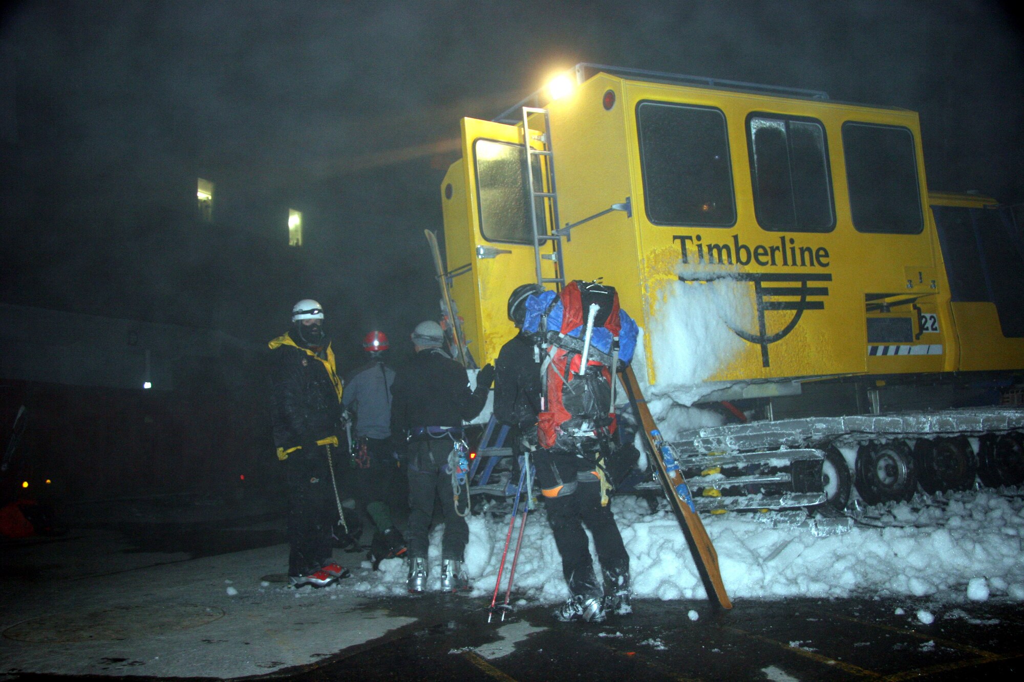Tech. Sgt. John Davis, 304th Rescue Squadron, Pararescueman (far left) waits outside of a snow cat to help the other members of the rescue team carry a skiing victim to a waiting ambulance, May 6, 2006.  The 304th pararescuemen were called out to help the Portland Mount Rescue and the American Medical Response Reach and Treat teams recover a man who tumbled down a three hundred foot slope while skiing on Mount Hood, Ore.