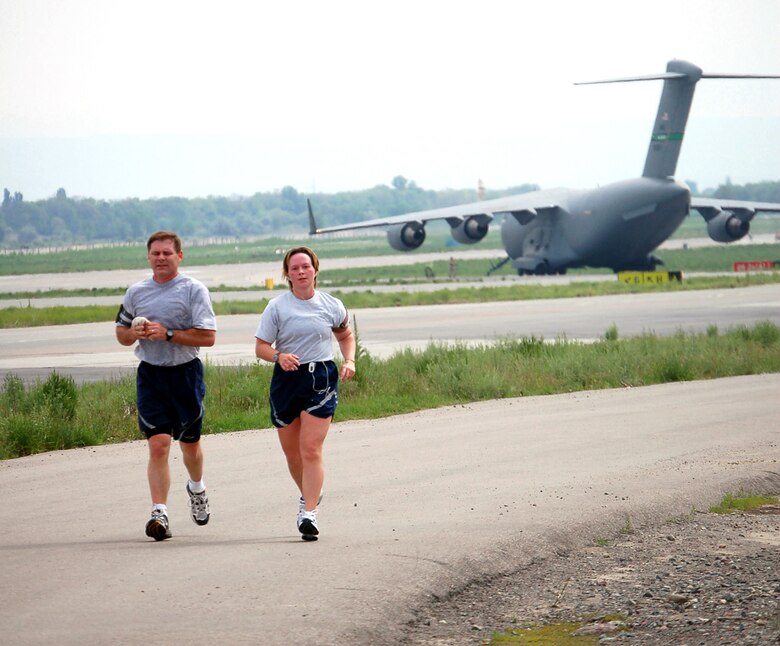 Master Sgt. Dan Wilcox keeps pace with Tech. Sgt. Jenny Livingston as they pass a C-17 Globemaster III on the final stretch of the Bloomsday Away 12K race at Manas Air Base, Kyrgyzstan, on Sunday, May 7, 2006. The Bloomsday race is annual tradition in Spokane, Wash. This year, Airmen brought their own version of the race to Manas. Sergeant Wilcox is with the 22nd Expeditionary Air Refueling Squadron and Sergeant Livingston is with the 376th Air Expeditionary Wing. (U.S. Air Force photo/Staff Sgt. Lara Gale) 