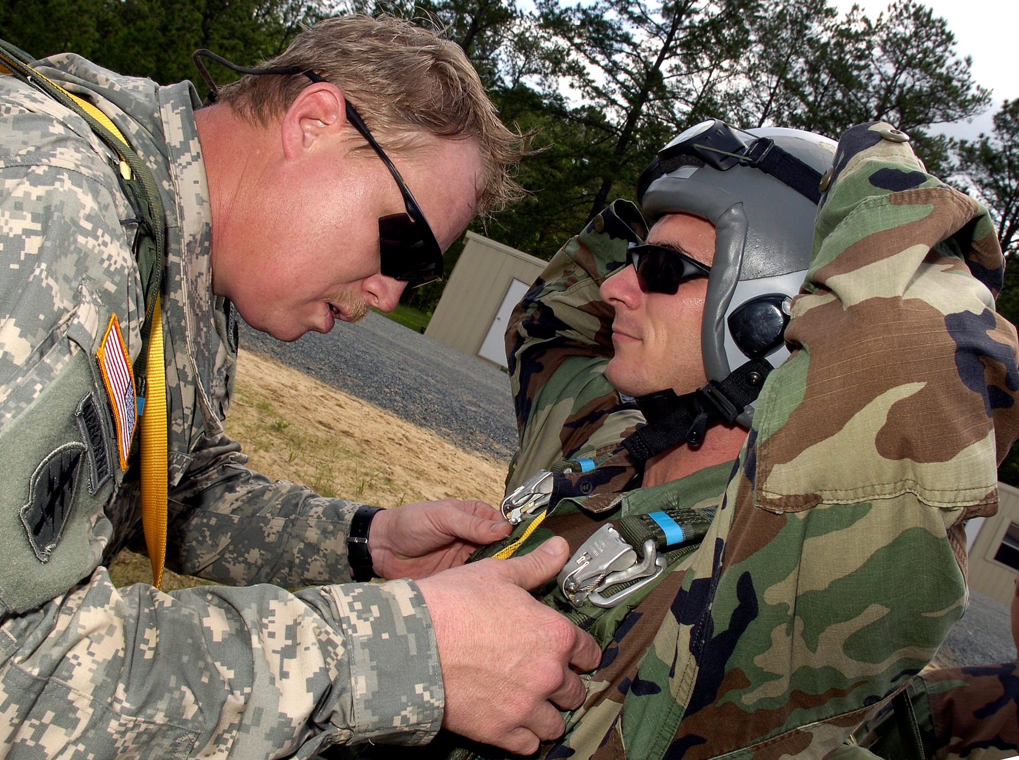 Army Master Sgt. Holland Wiler (left) performs a pre-jump inspection of Staff Sgt. Reed's parachute at the Joint Readiness Training Center at Fort Polk, La., on Wednesday, May 3, 2006. Sergeant Reed, a survival, evasion, resistance and escape specialist, jumped with special operations Soldiers to complete static-line parachute training. (U.S. Air Force photo/Senior Airman Stephen J. Otero)