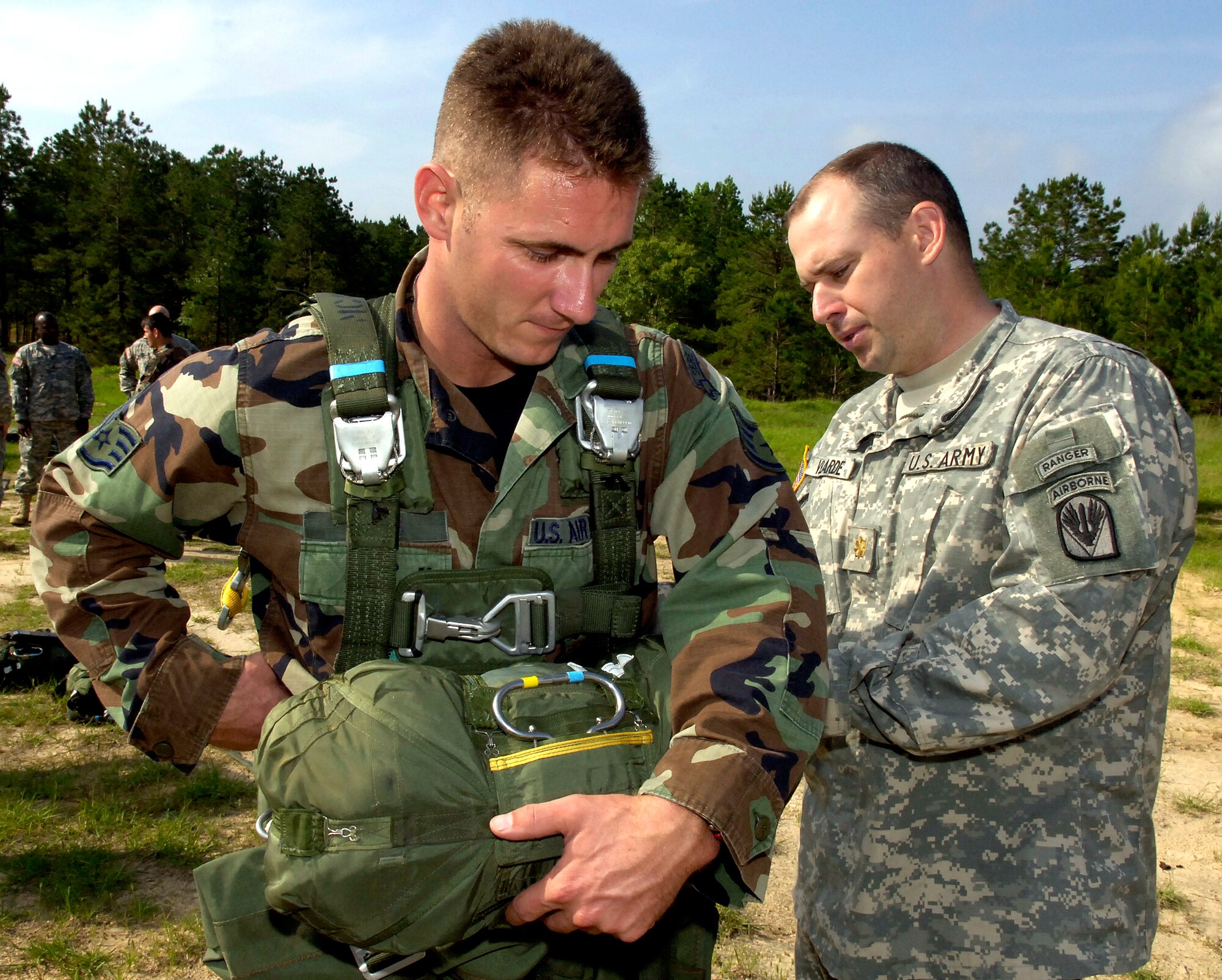 Staff Sgt. Reed (left) waits as Army Maj. Brian Velarde inspects his parachute at the Joint Readiness Training Center at Fort Polk, La., on Wednesday, May 3, 2006. Sergeant Reed, a survival, evasion, resistance and escape specialist, jumped with Soldiers in special operations training to complete static-line parachute training. (U.S. Air Force photo/Senior Airman Stephen J. Otero)