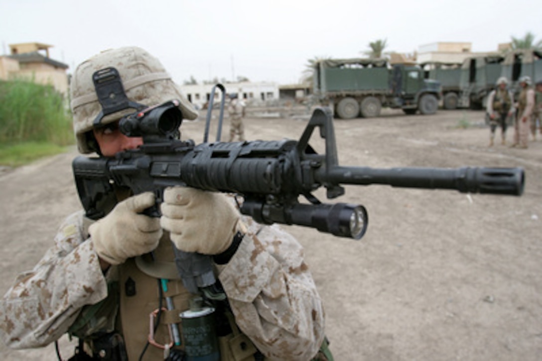 U.S. Marine Corps Master Sgt. John Dick scans the windows and rooftops of buildings surrounding the government center in Ar Ramadi, Iraq, on May 2, 2006. Dick is attached to the 3-2-1 Military Transition Team. 