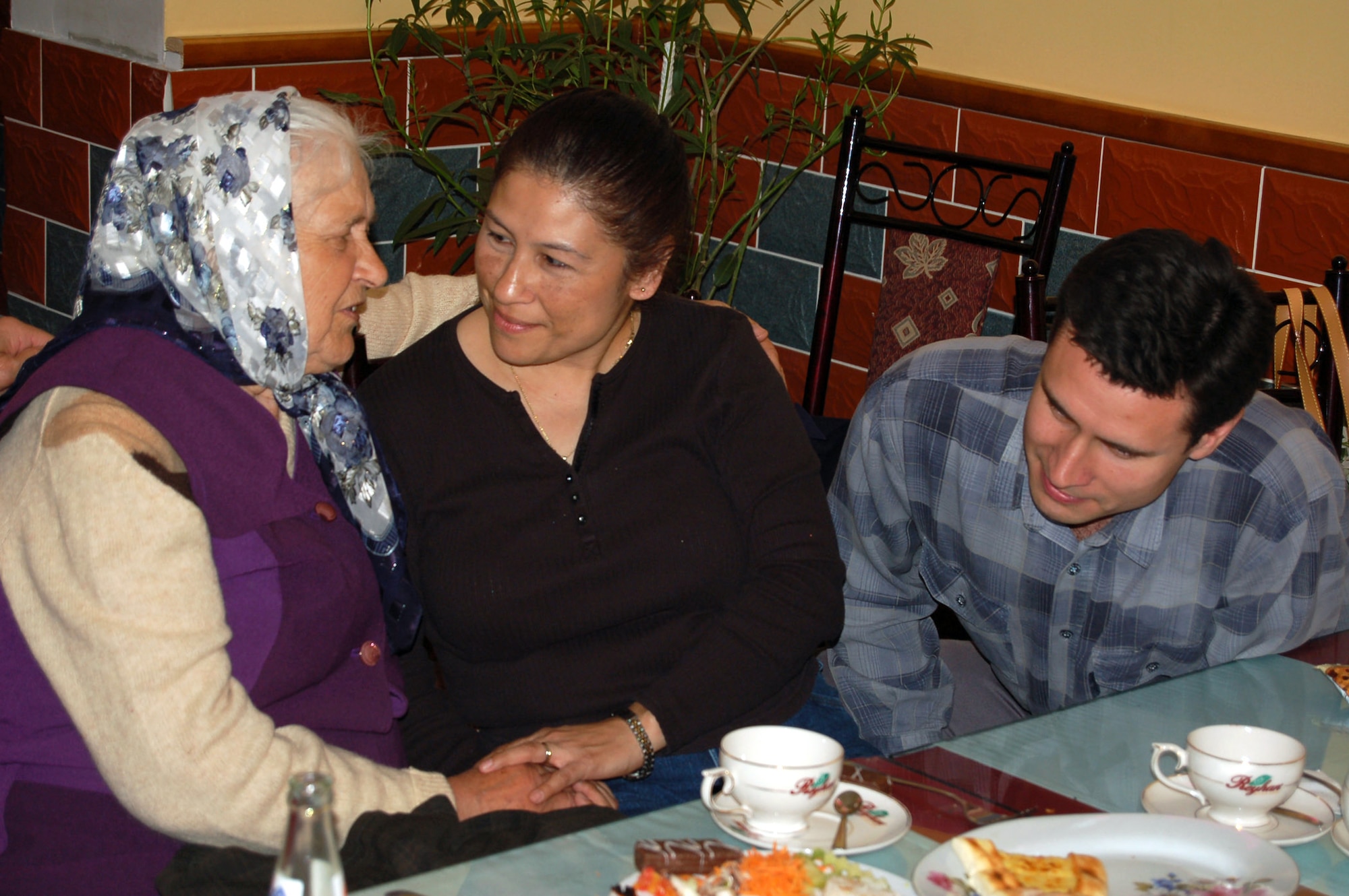 Olga sings a lullaby to Tech. Sgt. Victoria Querido during a lunch outing in Bishkek, Kyrgyzstan on Thursday, May 4, 2006. Sergeant Querido and Airmen from nearby Manas Air Base sponsor 20 elderly women who receive aid from Babushka Adoption. The local non-governmental organization assists elderly people left vulnerable as this post-Soviet nation works to stabilize its economy. Sergeant Querido is deployed from Fairchild Air Force Base, Wash. (U.S. Air Force photo/Staff Sgt. Lara Gale)
