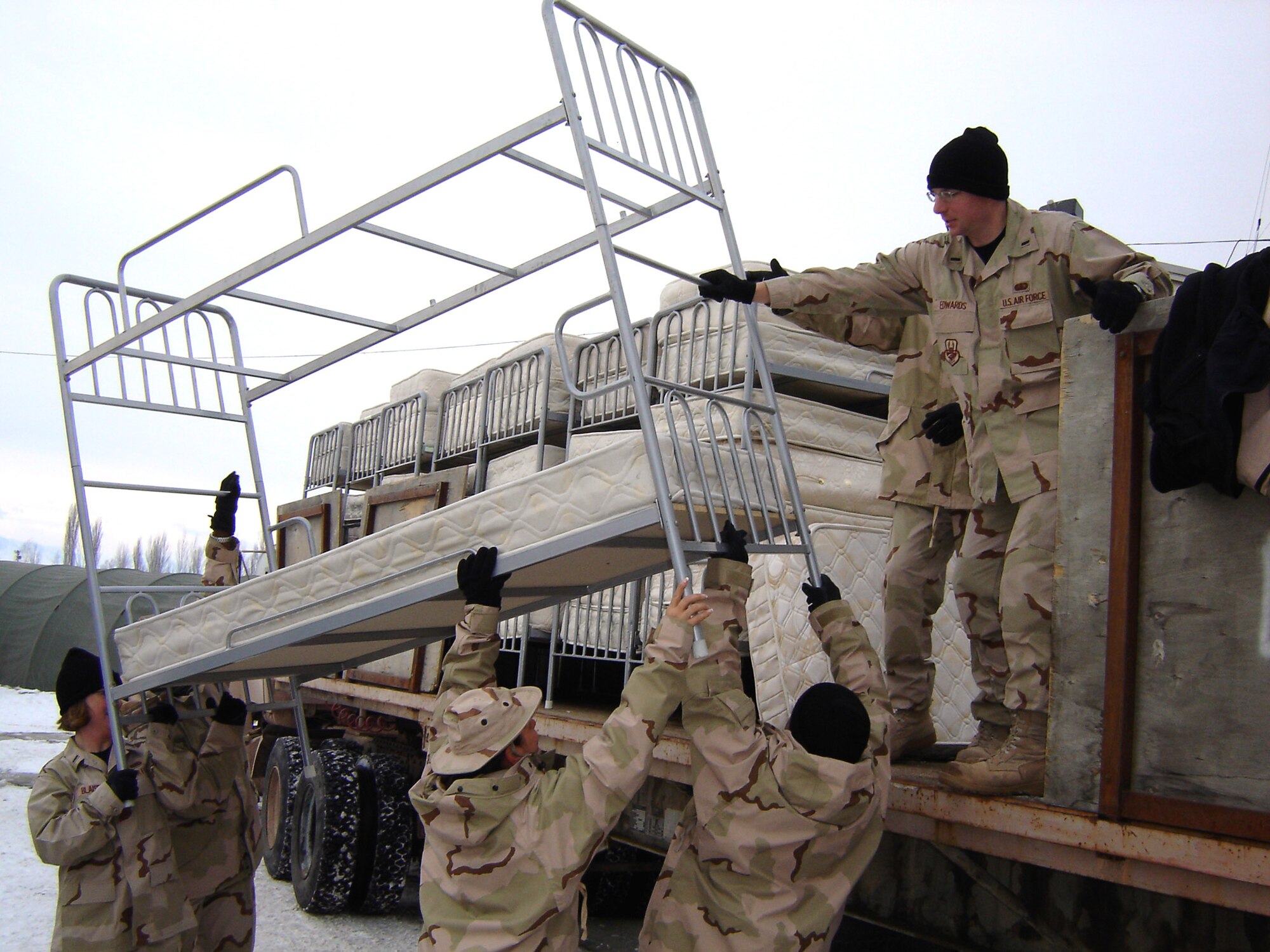 First Lt. Tyson Edwards (top) helps move bunkbeds at Manas Air Base, Kyrgyzstan. Airmen deployed to the 376th Expeditionary Services Squadron spent the first two weeks of their deployment creating more than 500 bedspaces for troops processing through the base en route to and from Afghanistan. (U.S. Air Force photo/Staff Sgt. Lara Gale)