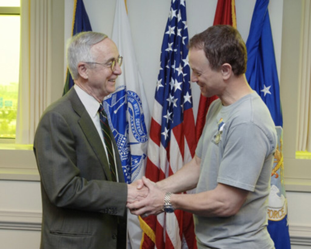 Deputy Secretary of Defense Gordon England congratulates actor Gary Sinise after presenting him with the Superior Public Service Award in the Pentagon on May 5, 2006. England presented Sinise the award in recognition of his work with the United Service Organizations tours and his visits with wounded heroes at Walter Reed Army Medical Center and the National Navy Medical Center. Sinise also co-founded the Operation Iraqi Children with author Laura Hillenbrand, in an effort to help educate Iraqi children. Sinise and his Lt. Dan Band will later perform at the Pentagon Center Courtyard. 