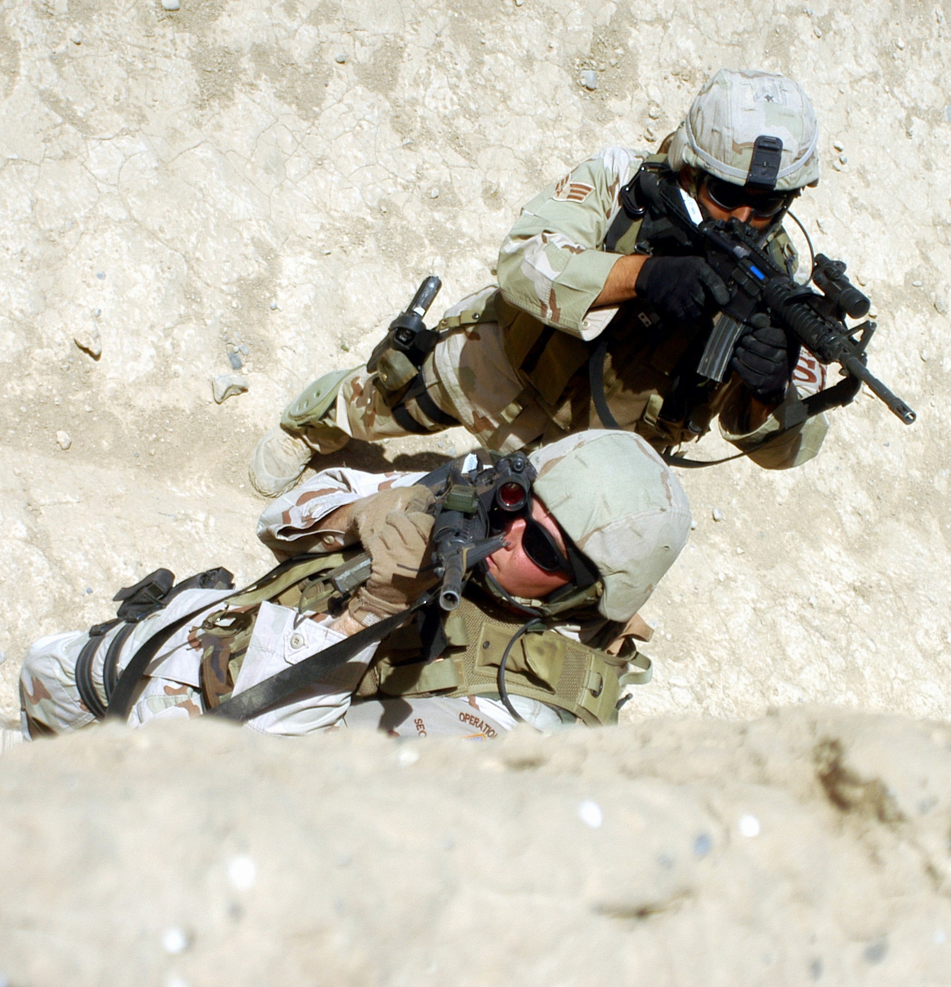 Senior Airman Charles Coles (foreground) covers a rooftop from the ground with an M-4 rifle during Military Operations in Urban Terrain training at Bagram Air Base, Afghanistan, on Tuesday, May 9, 2006. The facility here is designed to train Airmen and Soldiers in close-quarters combat with enemy forces. Airman Coles is with the 455th Expeditionary Security Forces Squadron. (U.S. Air Force photo/Maj. David Kurle)