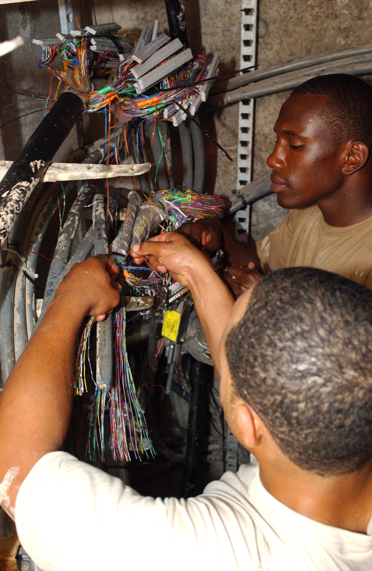Staff Sgt. Benjamin Puryear (front) and Senior Airman Jonathan Williams splice copper cables at Ali Base, Iraq, on Friday, May 5, 2006. They are with the 407th Expeditionary Communications Squadron's base information infrastructure shop. Sergeant Puryear is deployed from Andrews Air Force Base, Md., and Airman Williams is deployed from F.E. Warren AFB, Wyo. (U.S. Air Force photo/Master Sgt. Jon Hanson)