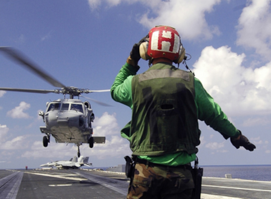 A U.S. Navy sailor guides an MH-60 Knighthawk onto the flight deck of the aircraft carrier USS Abraham Lincoln (CVN 72) during a vertical replenishment operation with the ammunition ship USNS Kiska (T-AE 35) on May 10, 2006. The Lincoln and embarked Carrier Air Wing 2 are operating in the South China Sea. The Knighthawk is assigned to Helicopter Sea Combat Squadron 25. 