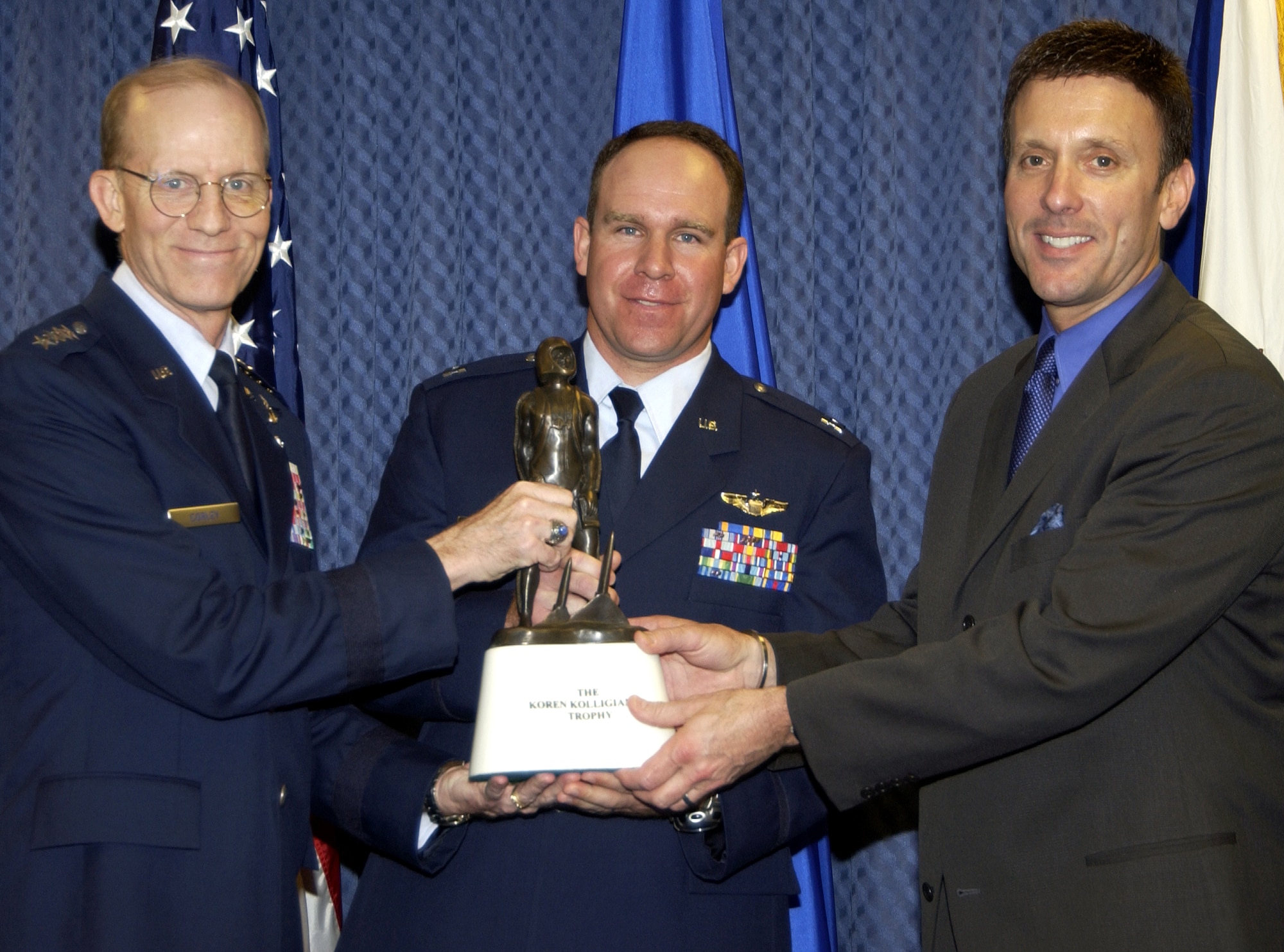 Air Force Vice Chief of Staff Gen. John D.W. Corley (left) and Koren Kolligian (right) present the Kolligian Trophy to Capt. Andreas  Ix during a ceremony in the Pentagon on Friday, May 12, 2006.  The trophy, named after 1st Lt. Koren Kolligian Jr., who was declared missing in the line of duty on Sept. 14, 1955, is awarded annually to an aircrew member or to aircrew members who exhibit outstanding feats of airmanship. Capt. Ix earned the award because of his actions after a red-tail hawk struck and damaged the C-17 Globemaster III he was piloting over West Texas on March 10, 2005. (U.S. Air Force photo/Mickey Sanborn)