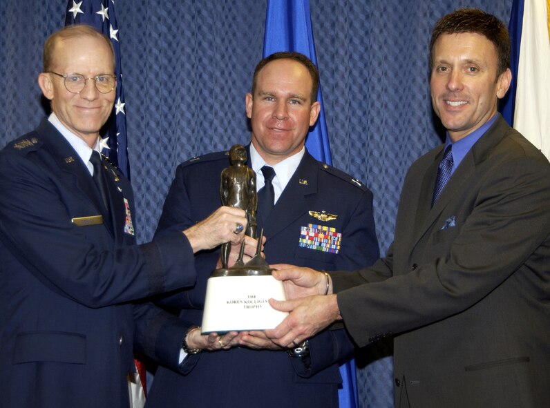 Air Force Vice Chief of Staff Gen. John D.W. Corley (left) and Koren Kolligian (right) present the Kolligian Trophy to Capt. Andreas  Ix during a ceremony in the Pentagon on Friday, May 12, 2006.  The trophy, named after 1st Lt. Koren Kolligian Jr., who was declared missing in the line of duty on Sept. 14, 1955, is awarded annually to an aircrew member or to aircrew members who exhibit outstanding feats of airmanship. Capt. Ix earned the award because of his actions after a red-tail hawk struck and damaged the C-17 Globemaster III he was piloting over West Texas on March 10, 2005. (U.S. Air Force photo/Mickey Sanborn)