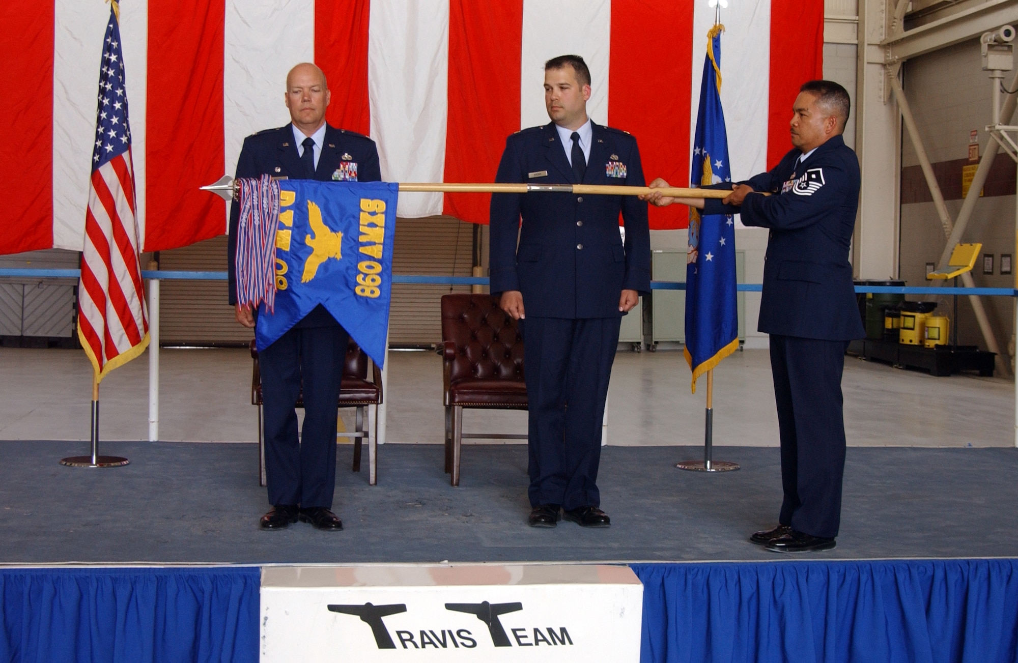Master Sgt. Abraham Redoble, 860th Aircraft Maintenance Squadron first sergeant, unfurls their squadron flag as Col. Keith Frede, 60th Maintenance Group commander, and Maj. Paul Brown, 860th AMXS commander, look on. The 860th AMXS officially activated in an assumption-of-command ceremony Wednesday. (U.S. Air Force photo by Nan Wylie)