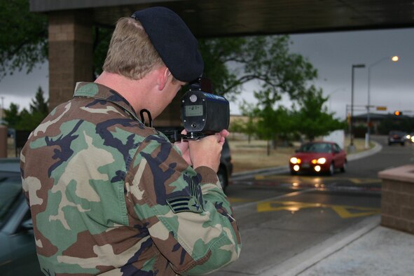 CANNON AIR FORCE BASE, N.M. --  Senior Airman William Nobel, 27th Security Forces,Squadron gets ready to clock a vehicle’s speed leaving the main gate at Cannon May 5. Drivers will notice an increased presence at the gates because of speeding vehicles, said Tech. Sgt. Rich Jones, 27th SFS. Vehicles speeding out the gate faster than the posted 5 mph causes damage to the pop-up barriers. Speeding tickets will cost active duty personnel at least three points. Non active duty individuals will be fined $15 for speeding one to 10 miles per hour over the posted speed limit. Sergeant Jones said plans are under way to install speed bumps to further deter speeding drivers. (U.S. Air Force photo by Greg Allen)