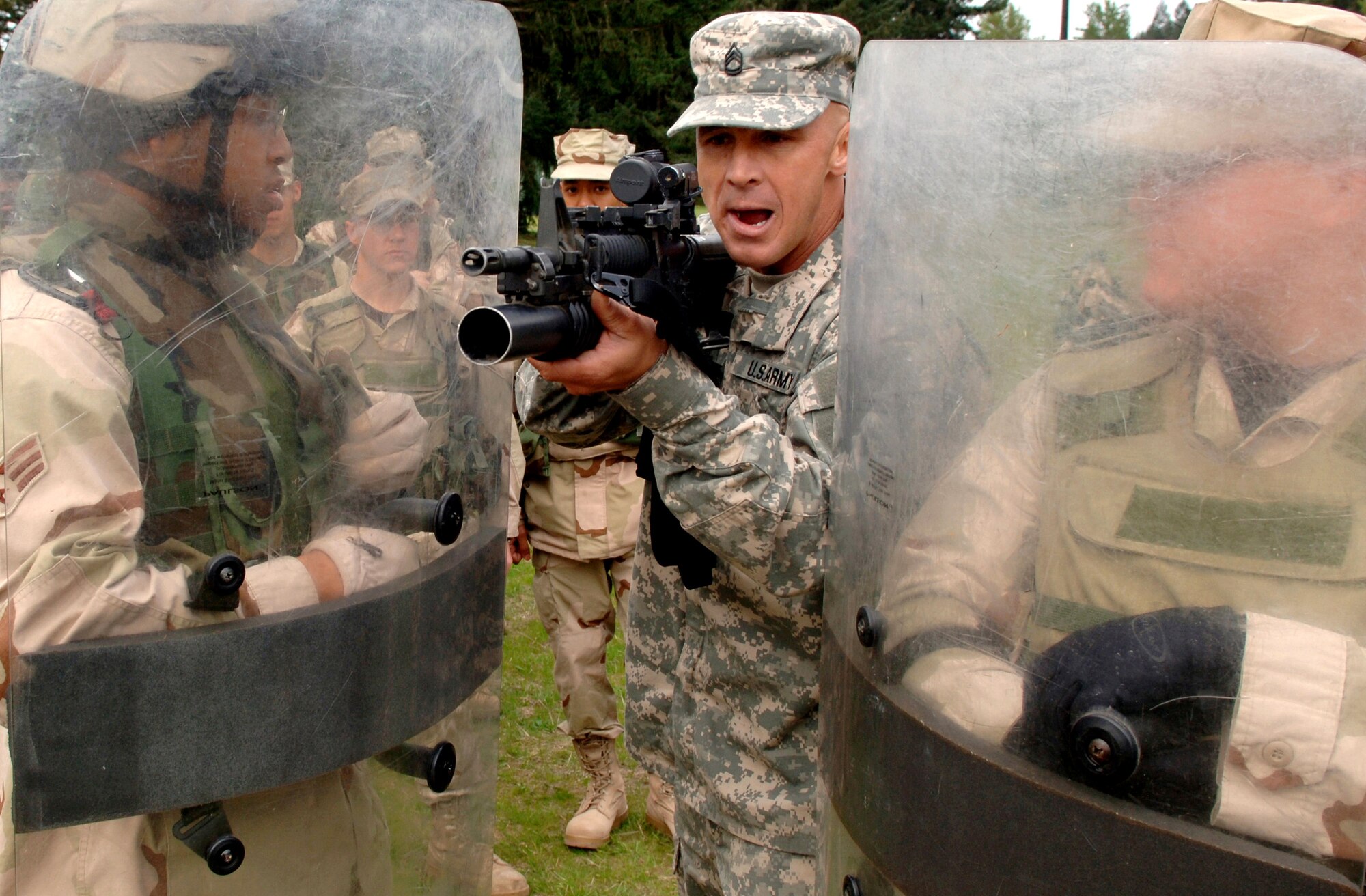 Army Sgt. 1st Class Troy Brown describes to Airmen undergoing detainee training operations on April 25, 2006, at Fort Lewis, Wash., the proper technique for firing from behind riot shields.  This training prepares Airmen by replicating situations they may encounter while deployed. (U.S. Air Force photo/Tech. Sgt. Larry A. Simmons)