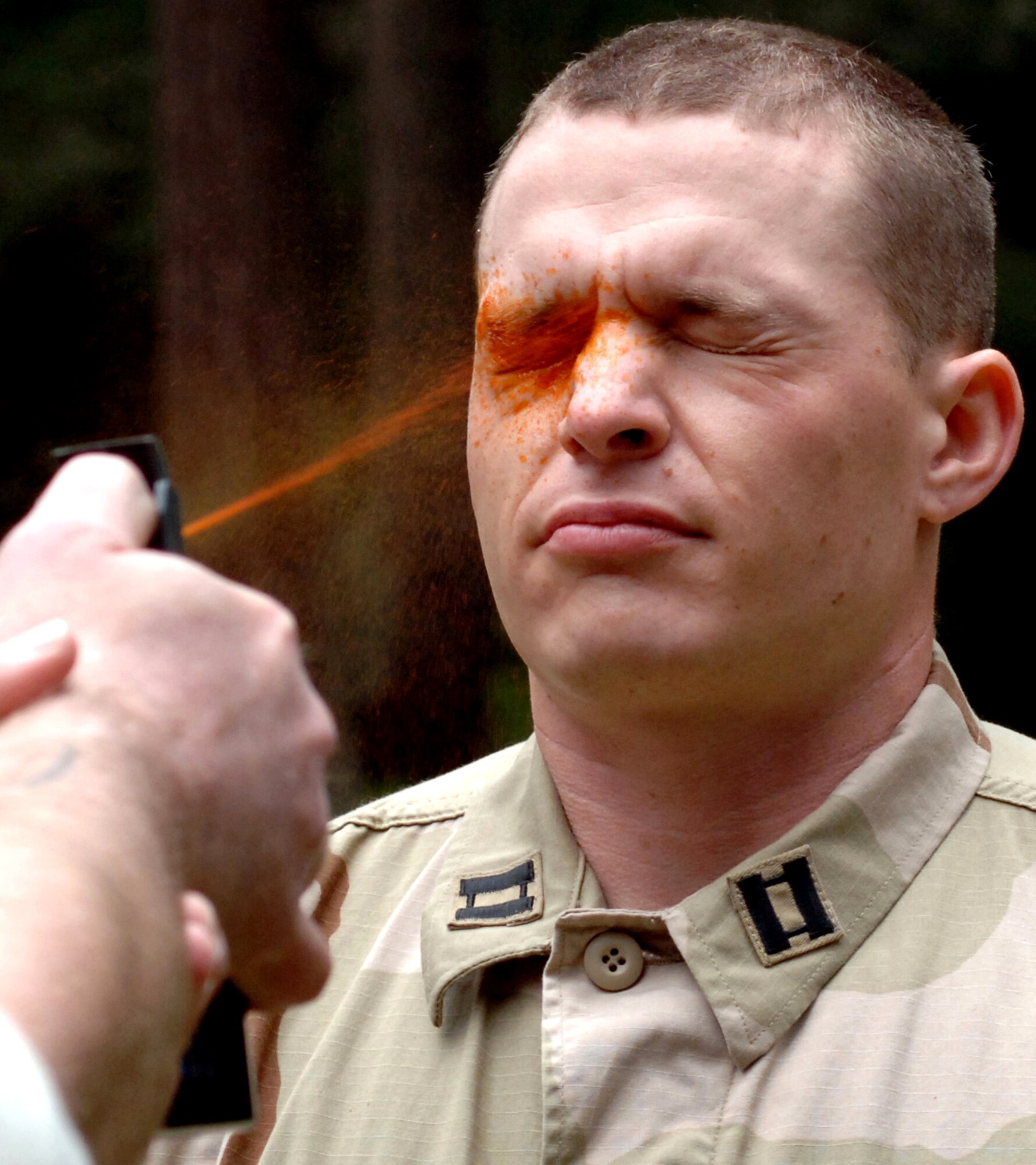 Capt. David Celeste gets sprayed with pepper-spray prior to running an obstacle course during detainee training operations on April 25, 2006, at Fort Lewis, Wash.  Airmen must navigate the course and take down a "hostile attacker" after being sprayed so they can learn how to function while feeling the effects of the spray.  This training prepares Airmen by replicating situations they may encounter while deployed.  Captain Celeste is with the 9th Security Forces Squadron at Beale Air Force Base, Calif.  (U.S. Air Force photo/Tech. Sgt. Larry A. Simmons)