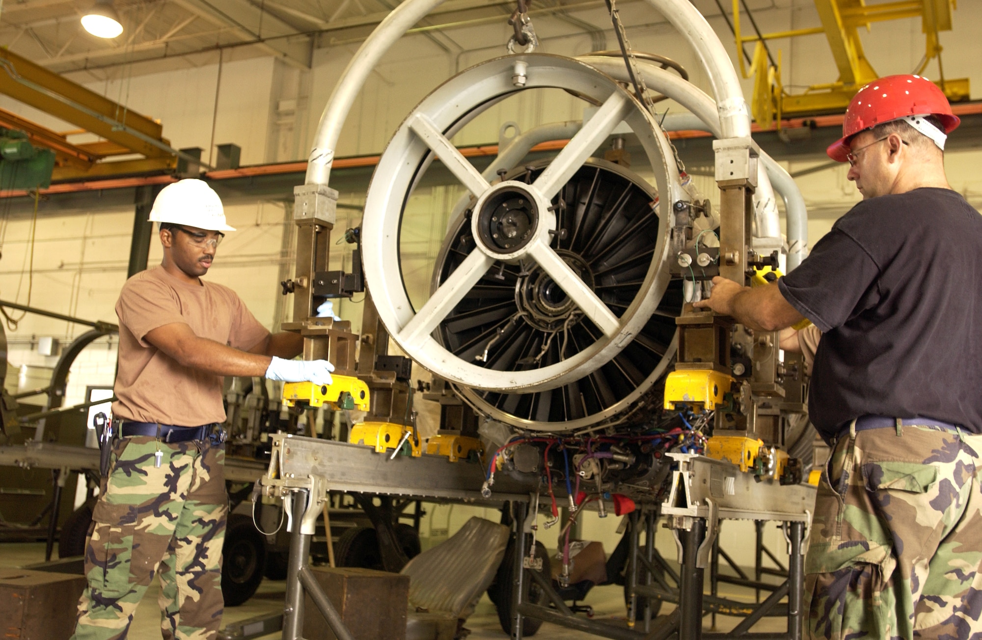 Senior Airman Michael Nathan (left) and Tech. Sgt. Darren Small lower a maintenance adapter into place to support the fan module of an F-15 Eagle engine on May 10, 2006.  The engine was undergoing repair for damage caused by foreign object debris, known as FOD.  Airman Nathan and Sergeant Small are aerospace propulsion technicians at the Florida Air National Guard's 125th Fighter Wing in Jacksonville. (U.S. Air Force photo/Staff Sgt. Shelley Gill)