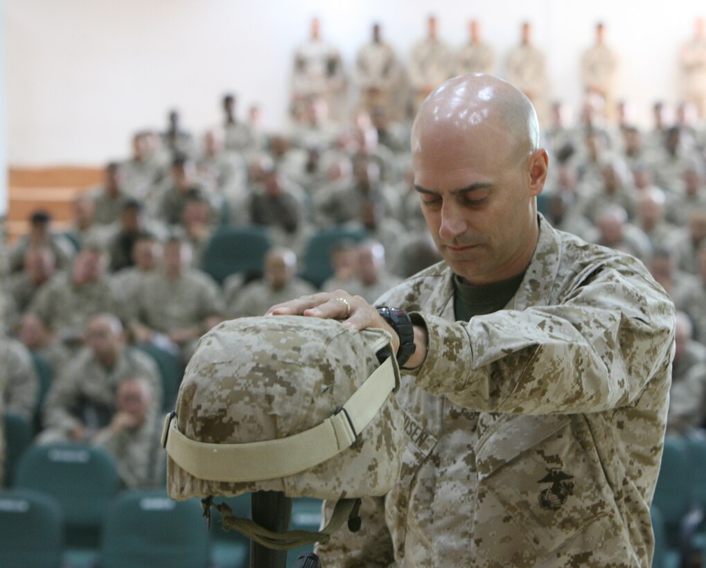 Major Steven R. Svendsen, executive officer for Combat Logistics Battalion 5, places his hand on the helmet used to honor Lance Cpl. Leon B. Deraps, a combat engineer with Company C, who was killed by an improvised explosive device on May 6, 2006 while providing engineering support in the Al Anbar Province. Deraps, a native of Jamestown, Mo., was considered a kind-hearted and caring friend, one who put everyone ahead of himself. His awards include the Purple Heat, National Defense Service Medal, the Global War on Terrorism Service Medal, and the Iraqi Campaign Medal.